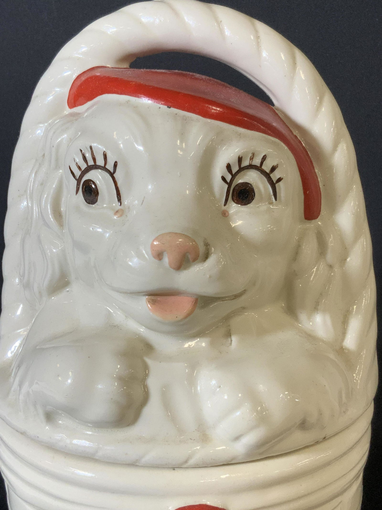 Vintage AMERICAN BISQUE Dog Lidded Cookie Jar: Vintage lidded white ceramic cookie jar shaped a dog sitting in a basket. The dog has a red hat on, brown eyes, and a pink nose & tongue. The dog and basket handle are the lid. Basket with red bow acc