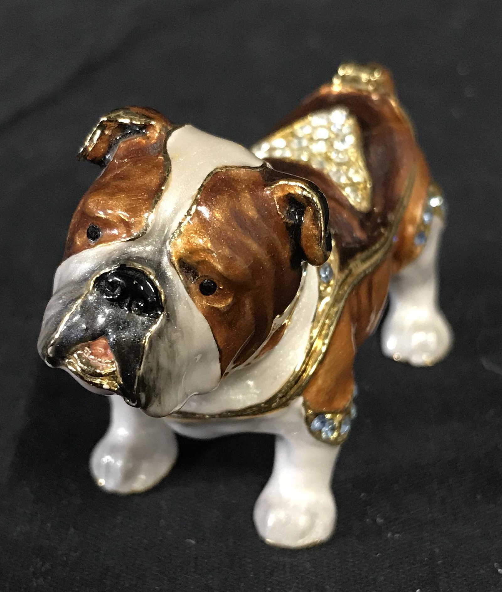Bejeweled Enameled Bull Dog Trinket Box: Bejeweled Trinket box, bull dog formed, Crafted from enamel and metal. The lid is hinged, a mark can be found on the box’s interior, resembles a K in a Crown. Measures approx 1.75 inches H, 3 inches