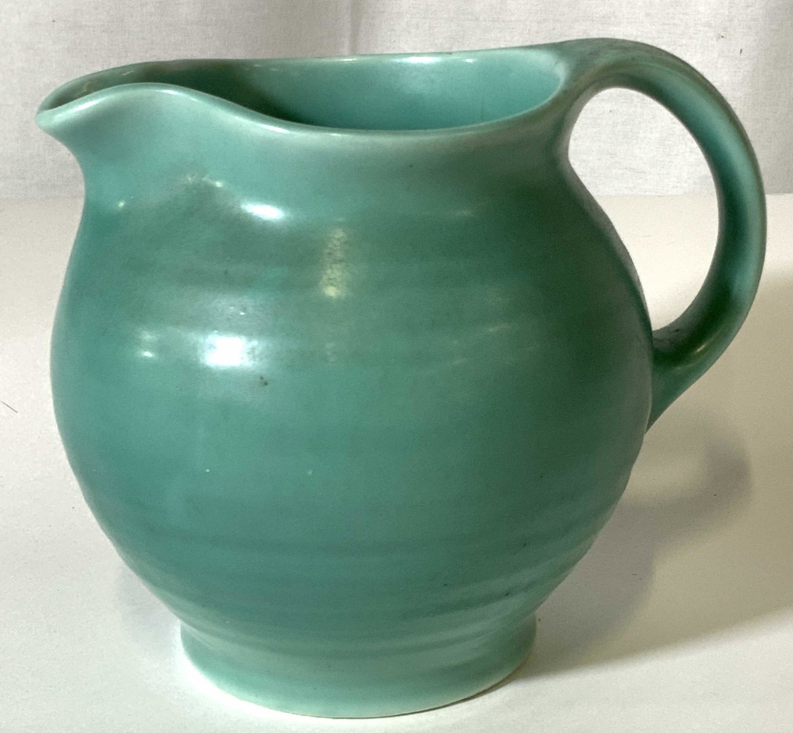 Signed CROWN Ceramic Teal Pitcher: Ribbed ceramic pitcher, c. 1940s. Hallmarked on verso, words illegible. 5 in ht. 6.5 in. Length with handle, 5 in with. Ceramics, pottery, pitcher, teal, tableware, tabletop, pitcher vase, Ceramic pit