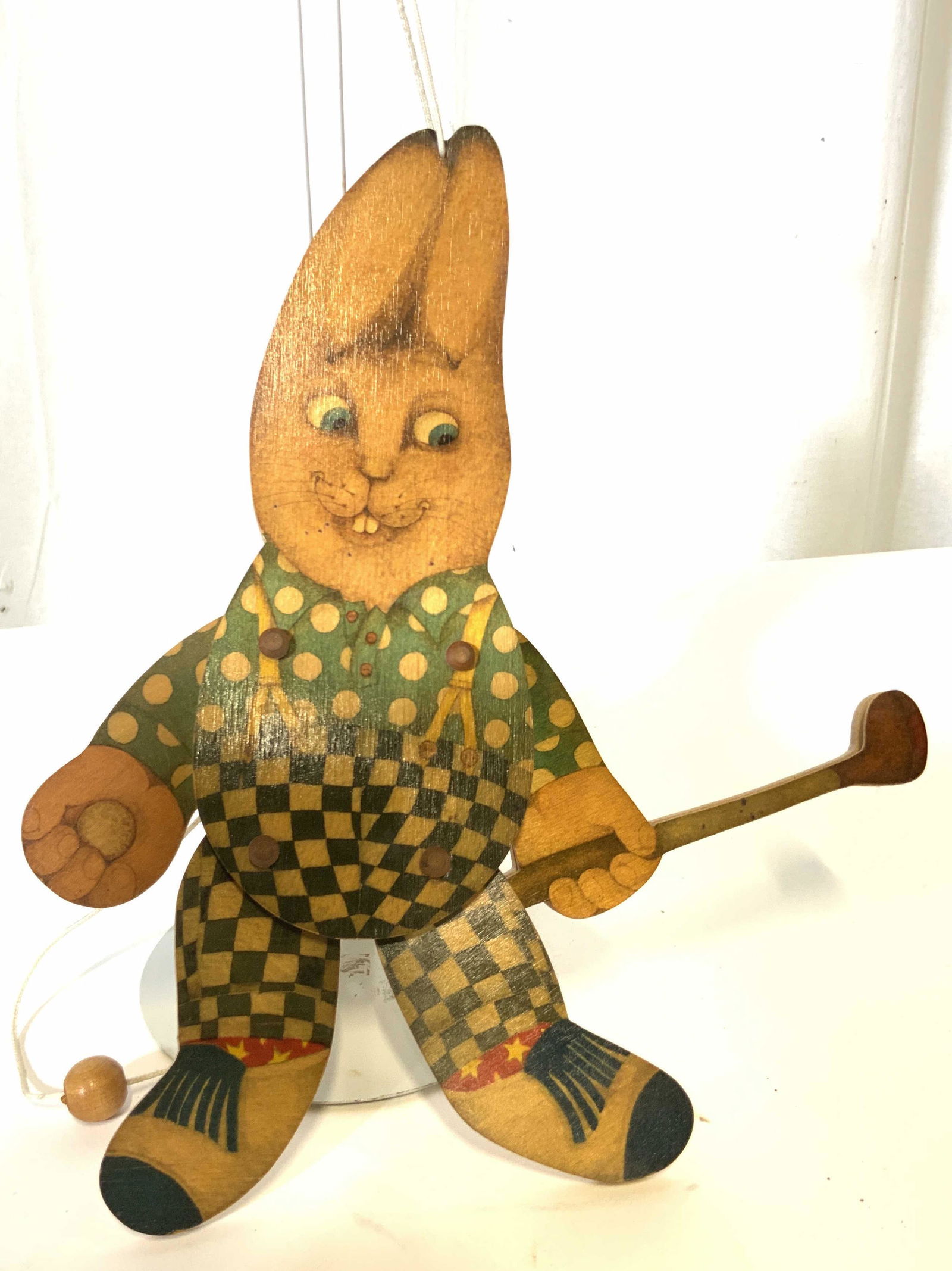 Vintage Collectible Wood Rabbit Puppetry Toy: Flat toy depicting transfer illustration of buck toothed rabbit in polka dot shirt and checkered pants. holding a golf club. Top string and moveable string pulls arms and legs up when string is pulled