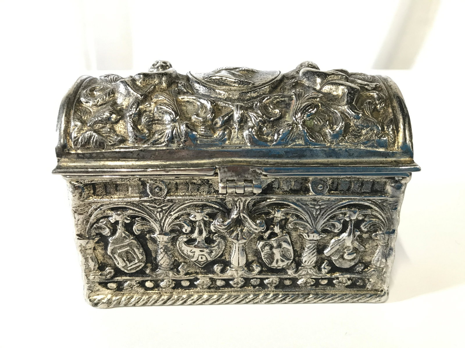 Intricately Detailed Pewter Trinket Box Chest: Trinket box is silver toned and pewter. Piece has intricate detail with ornate areas. Trinket box is lidded. Piece measures approximately 4.5 inches long 3.5 inches tall 2.5 inches deep. Trinket box, 