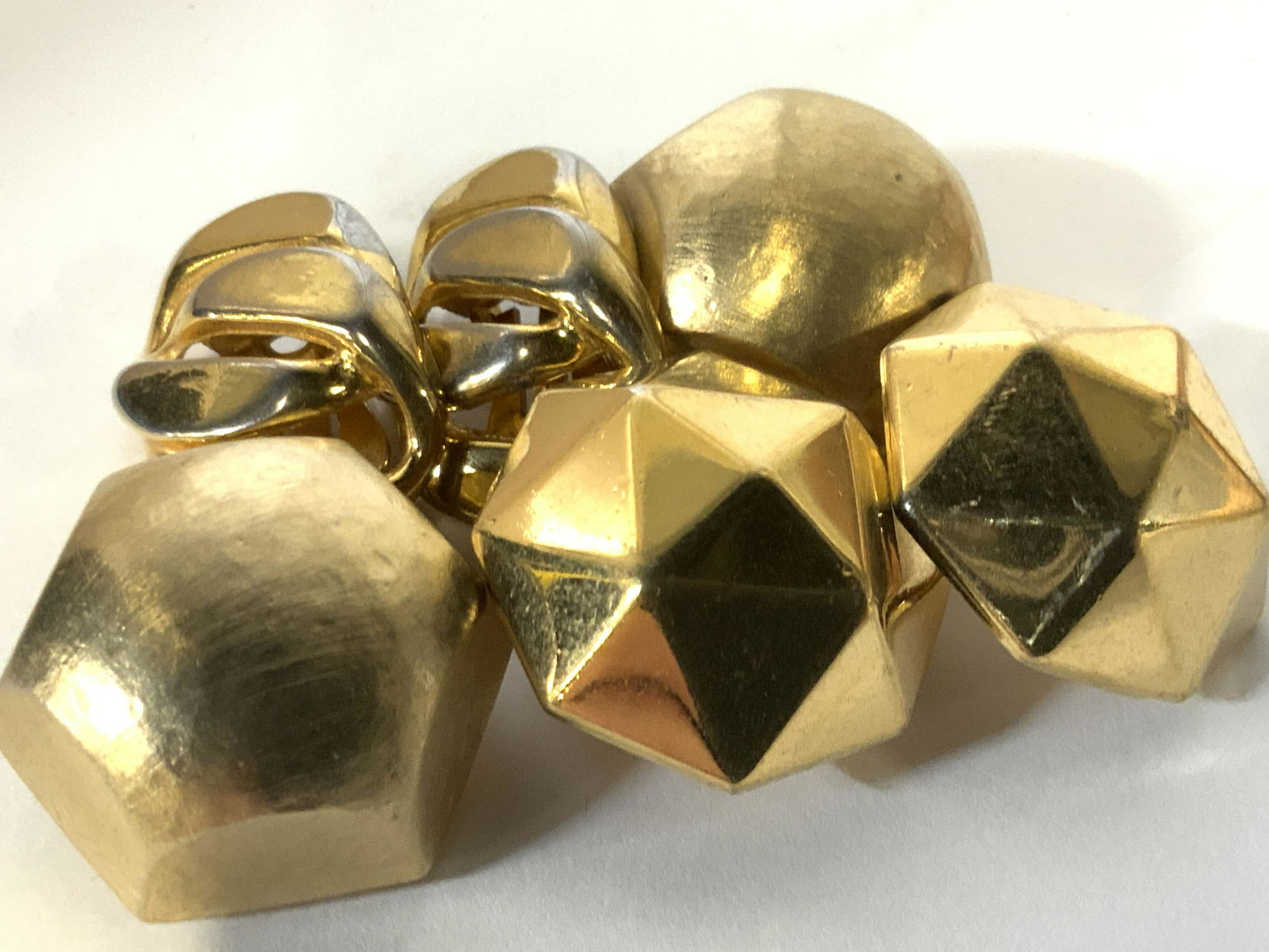 Lot 3 Clip on Earrings, MONET, More: All gold toned earrings. All clip on earrings . Signed Monet geometrical triangle pattern 1 1/8 in wide. Hammered metal hexagonal earrings with rounded facade. 1.25 in wide. Clip on flat chain link ea