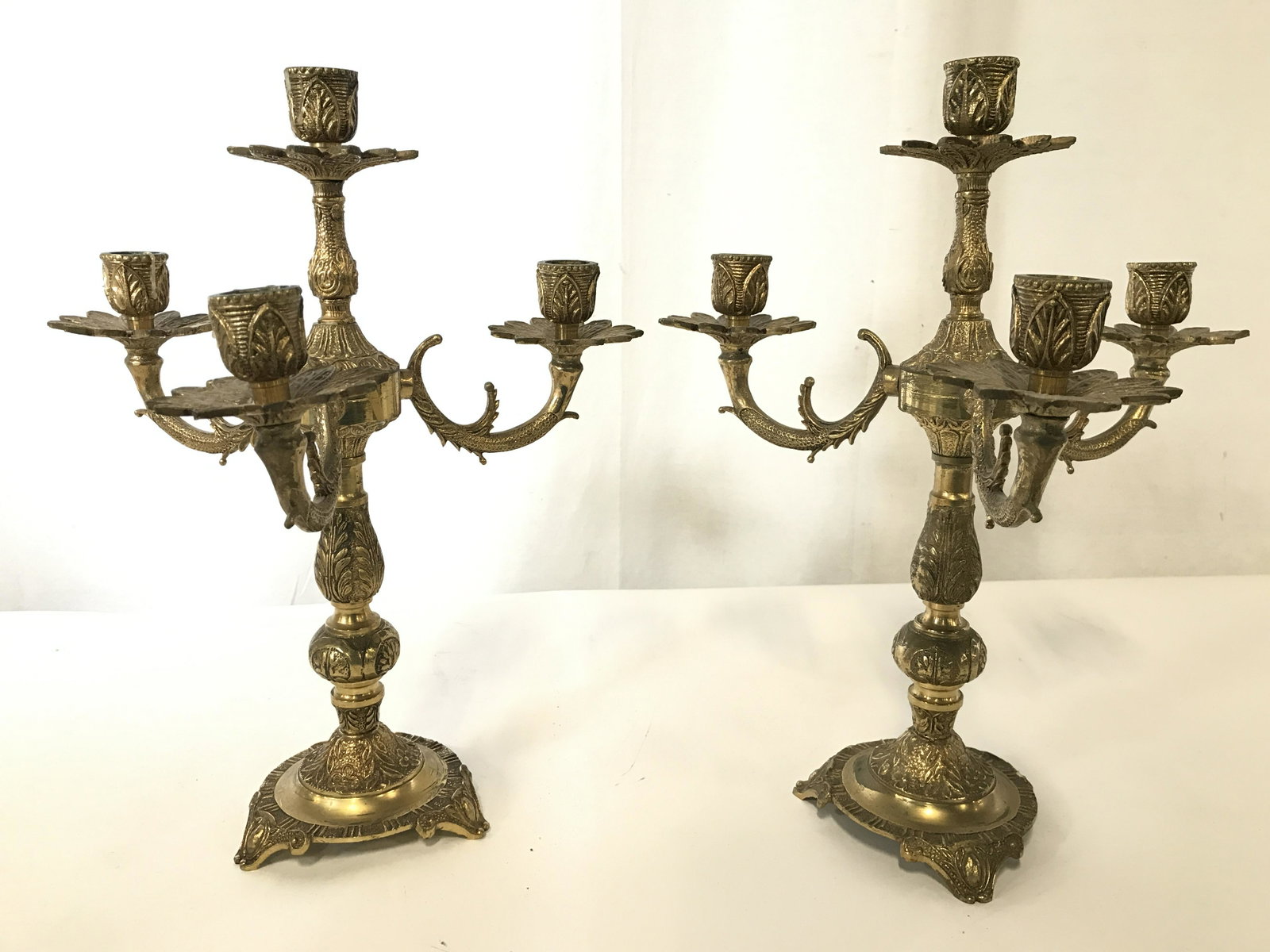 Pair Vintage Gold Toned Brass 3 Arm Candelabras: Candelabras are gold toned and brass. Each appear to be vintage. Candelabras Each have 3 arms with 1 center arm. Each piece has 3 feet. Candelabras have ornate detail. Each measures approximately 14 i