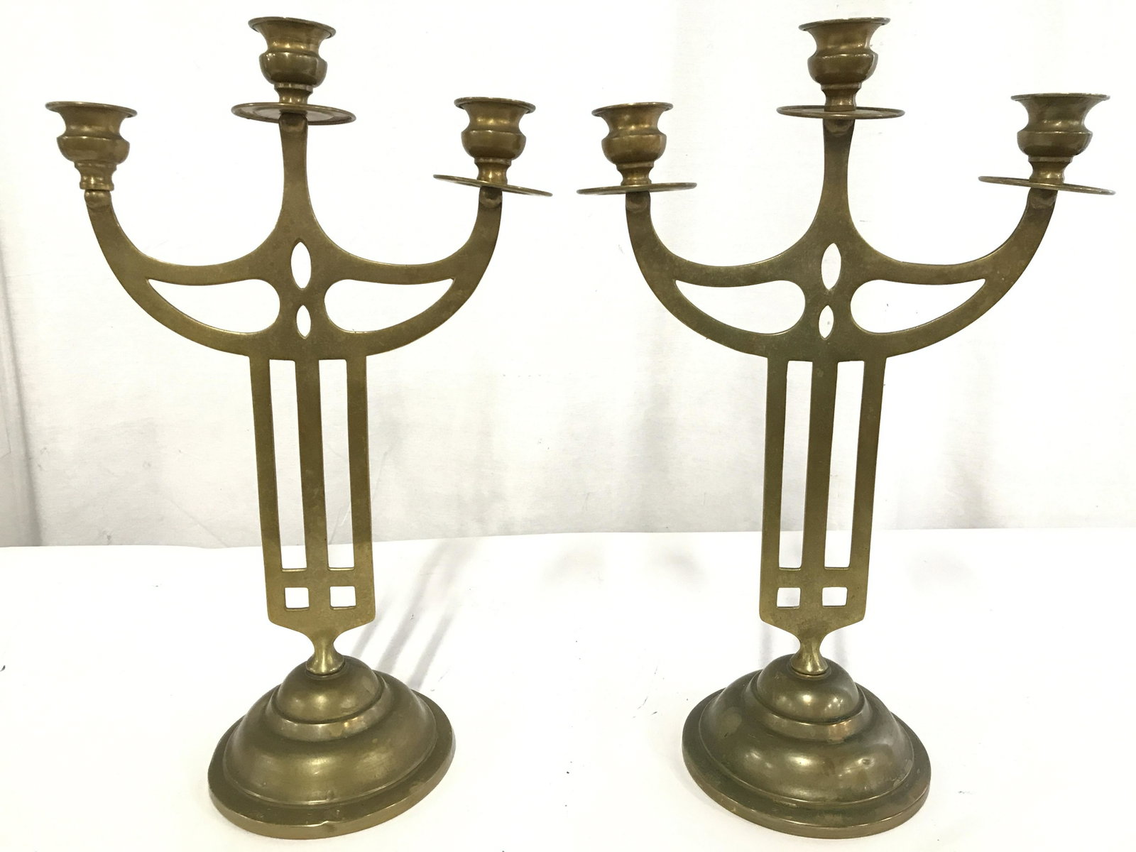 Pair Vintage Gold Toned Brass 2 Arm Candelabras: Candelabras are gold toned and brass. Each have 2 arms with 1 center arm. Candelabras have circular bases. Each have pierced detail. Candelabra measures approximately 16 inches tall 10 inches wide 5 i