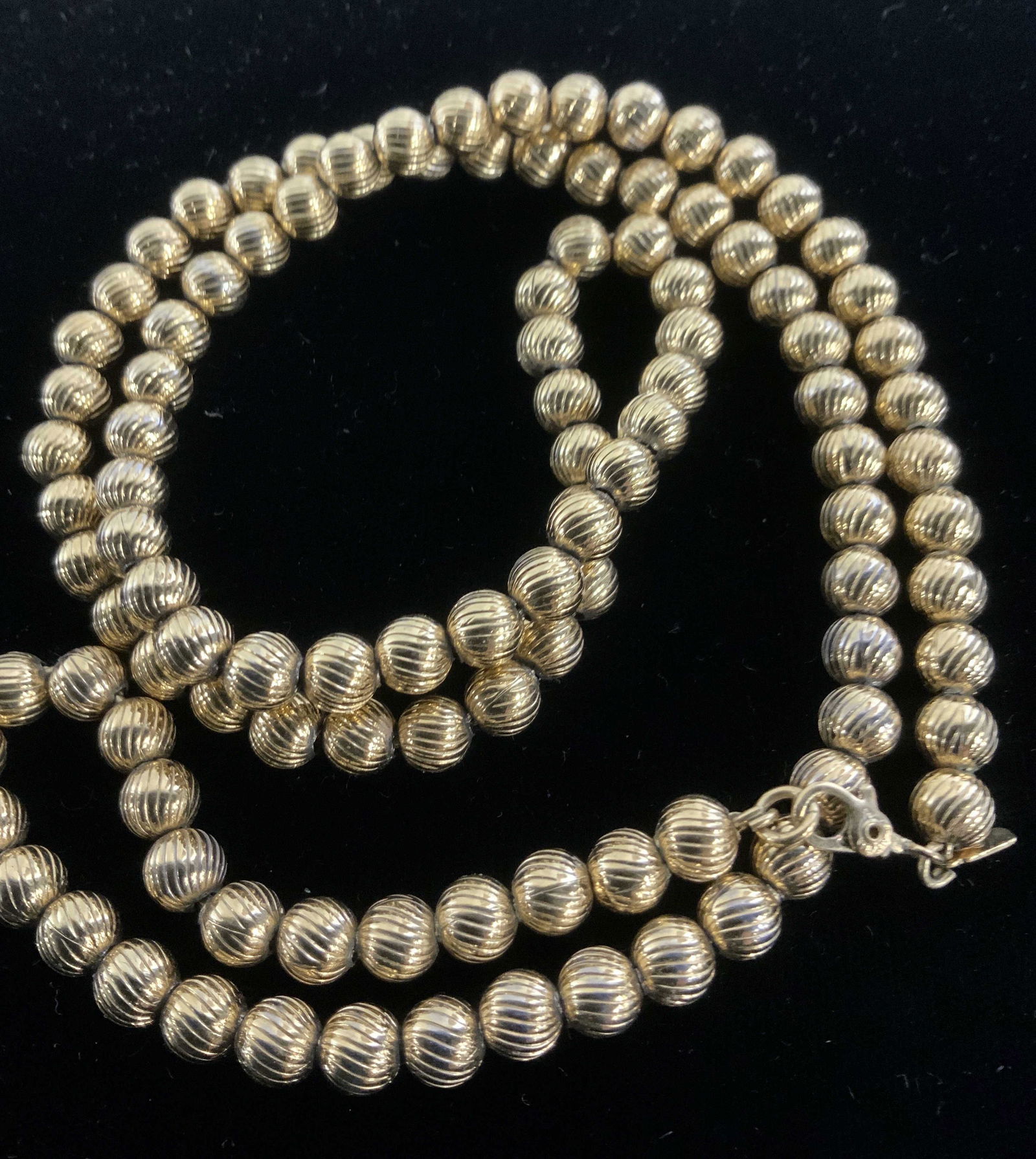 Signed MONET Costume Beaded Necklace: Chased Lined Round beaded necklace, signed Monet on charm, lobster clasp, gold toned metal, 26 in long. Beads 3/8 in. Possibly vintage. Signed Monet Necklace, Gold Toned Beaded Monet Necklace, Monet C