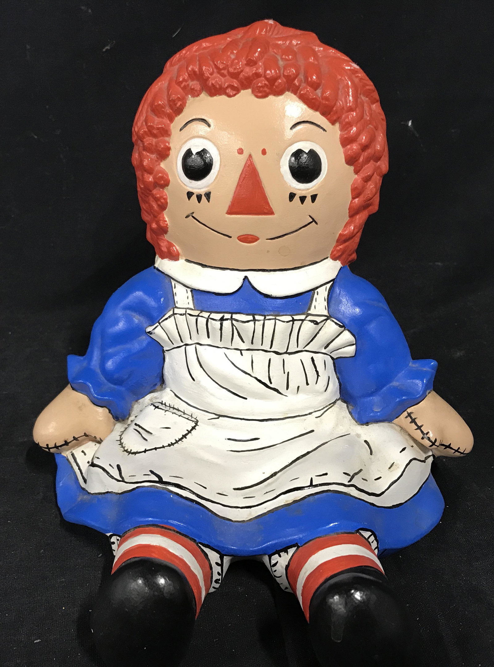 Signed Ceramic Hand Painted Raggedy Anne Figural: Signed Ceramic hand painted raggedy Anne, signature and date to underside reads ‘Sue 75’, text to underside illegible, subject the character raggedy Anne in a blue dress with a white apron, some s
