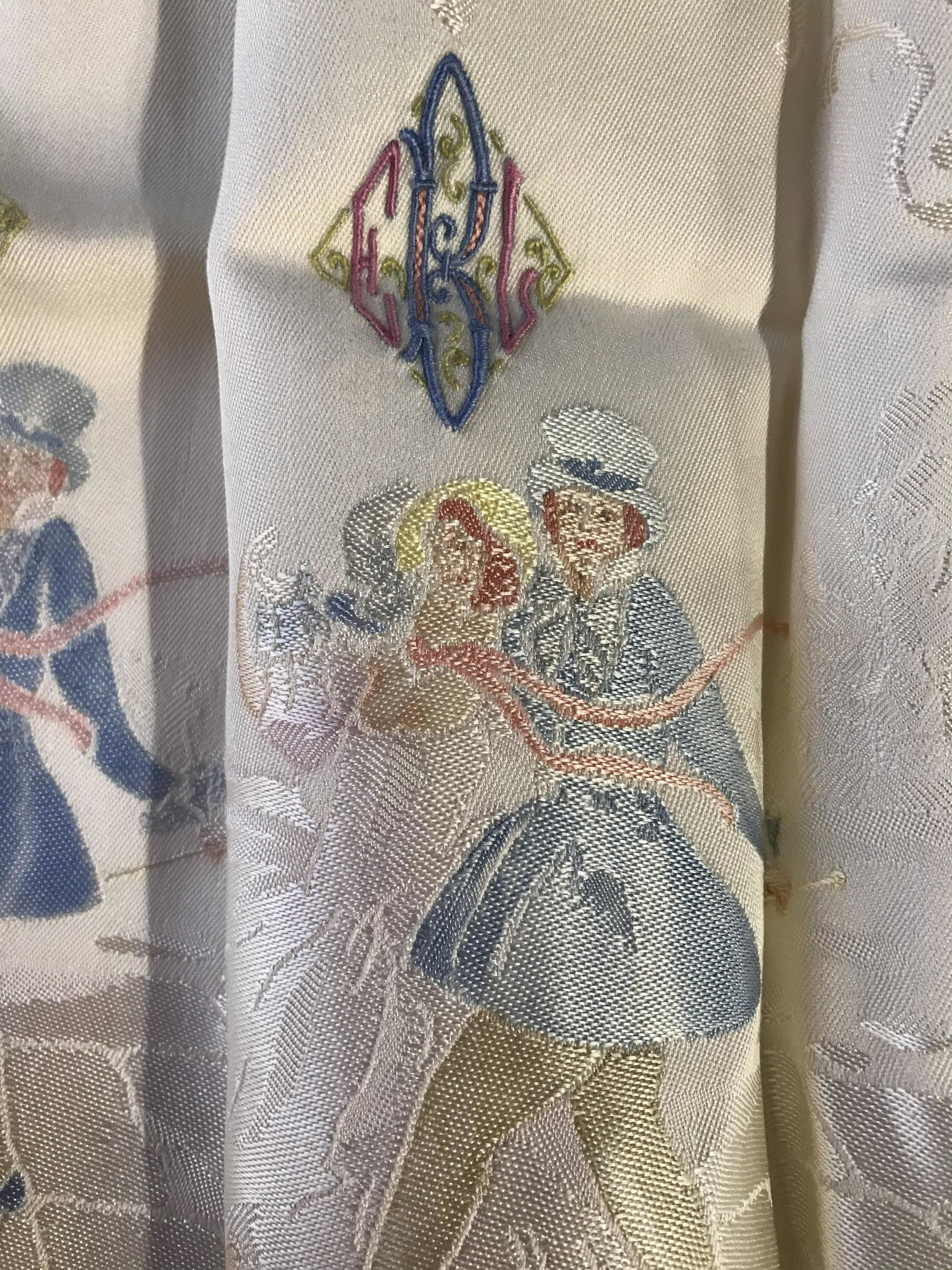 Set 13 Embroidered Table linens: Set of 13 table linens, includes a table runner/table cloth, and 12 napkins. Napkins and tablecloth depict a man and woman walking through a city. Largest measures approx 58 inches W, and 83 inches lo