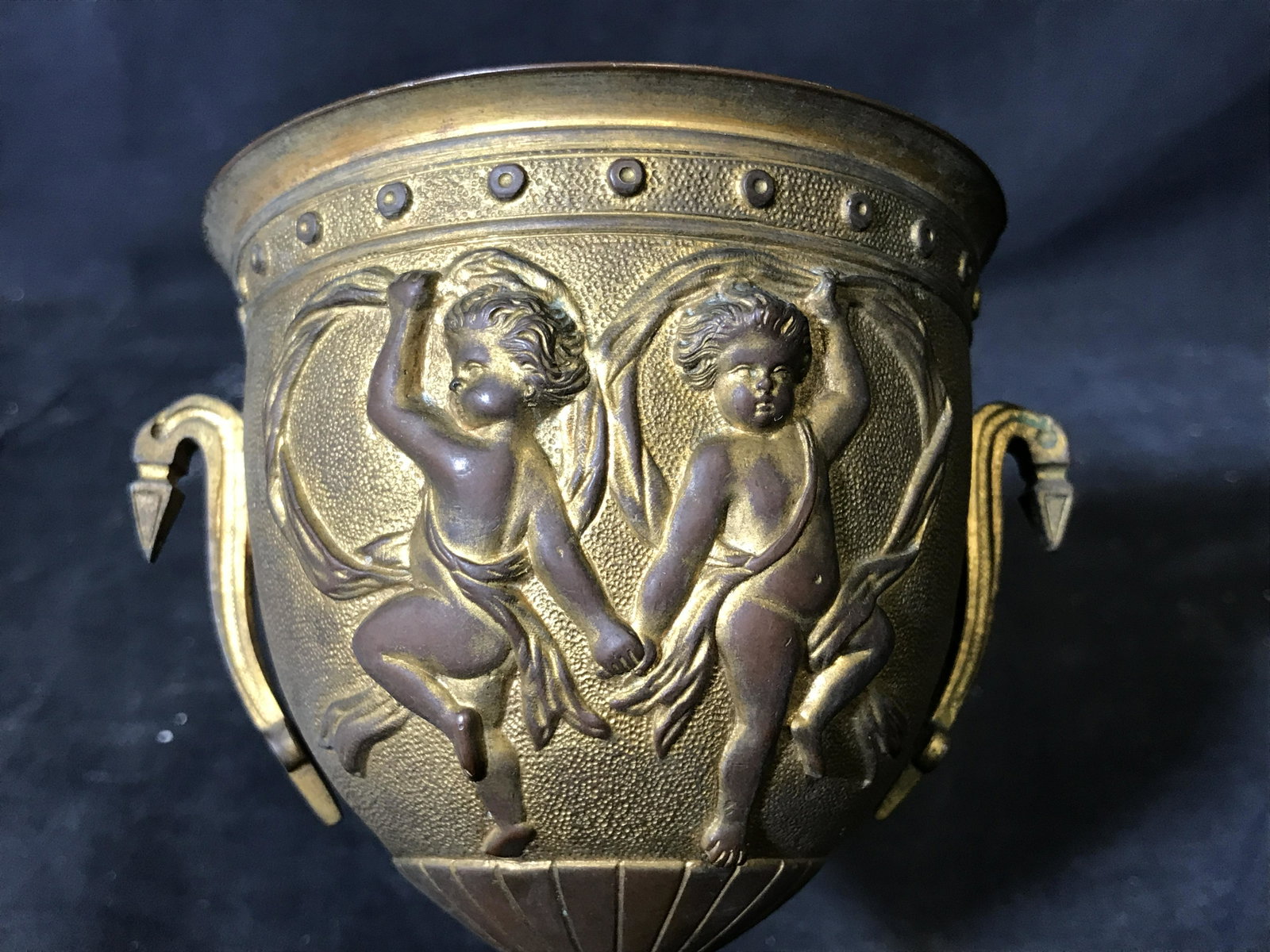Brass Goblet Vessel with Cherubs: Brass Goblet with cherubs, no apparent signatures or stamps, exterior of cup decorated with dancing cherubs and geometric designs, some oxidation to surface, measures 5.75 inches at tallest, measures 