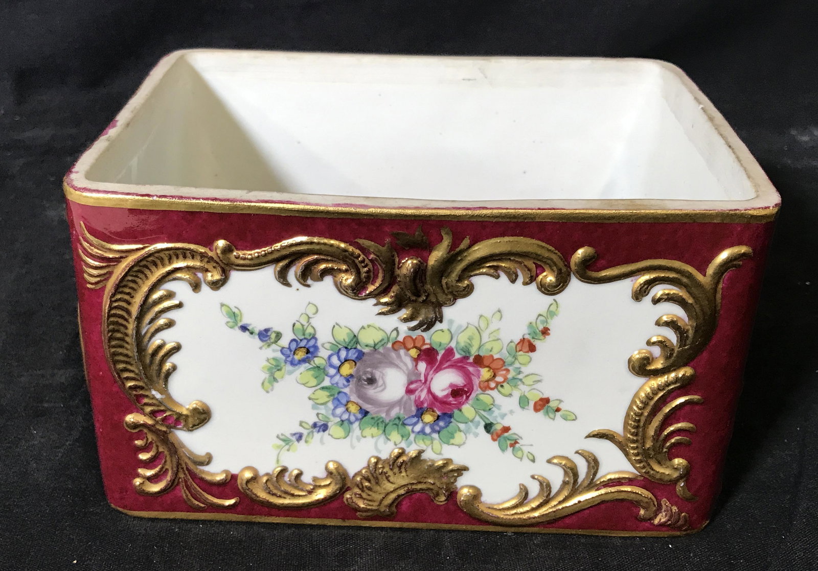Hallmarked Porcelain Rococo Hand Painted Vessel: Porcelain Rococo hand painted box, stamp to underside displays the letter S in a box, exterior walls of the box display floral designs in a border of painted gold leaf designs and a base color of cran