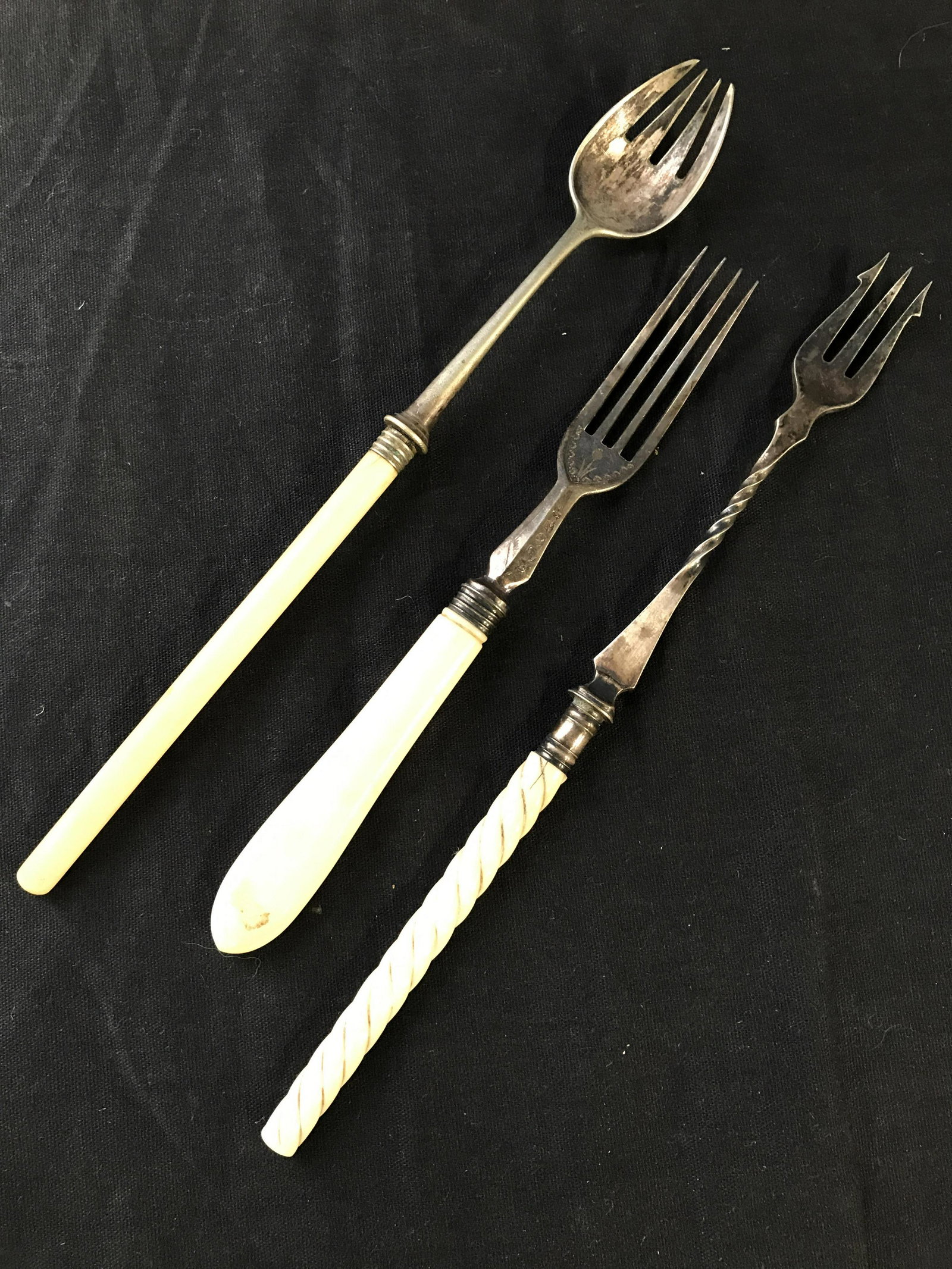 Lot 3 Carved Bone Handle Tableware: Lot includes 1 4 pronged fork, 1 3 pronged fork, & 1 spork. Each piece of silverware has carved bone handles. Each piece appears to be vintage. Largest piece measures approximately 8.5 inches long .75