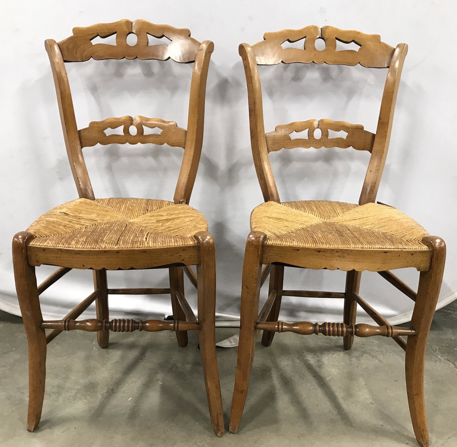Vintage Carved Wooden Rush Seat Side Chairs: Side chairs are vintage possibly antique. Each are wooden with carved detail. Possibly hand crafted. Both chairs have rush seat. Each chair has wooden stretchers between legs. Each measures approximat
