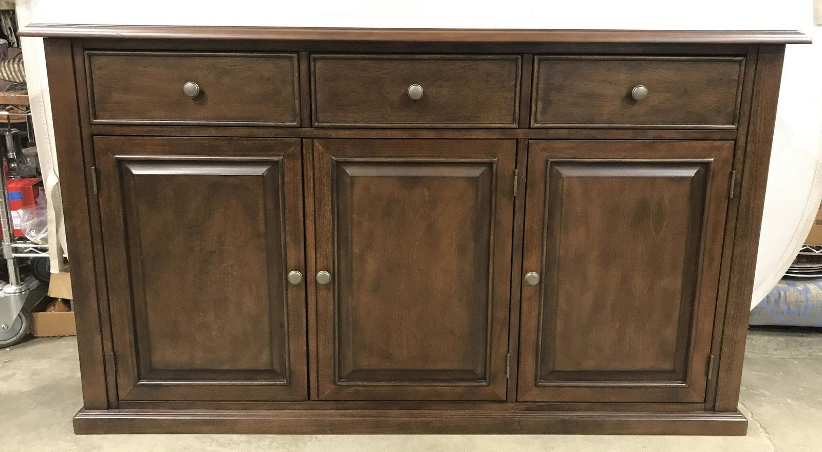 Brown Toned Wooden Console Table Sideboard: Sideboard is brown toned and wooden. Piece has 3 drawers & 3 cabinet doors. Drawers each have gold toned metal knob style handles. Console table, buffet, sideboard, wooden sideboard, wooden console ta