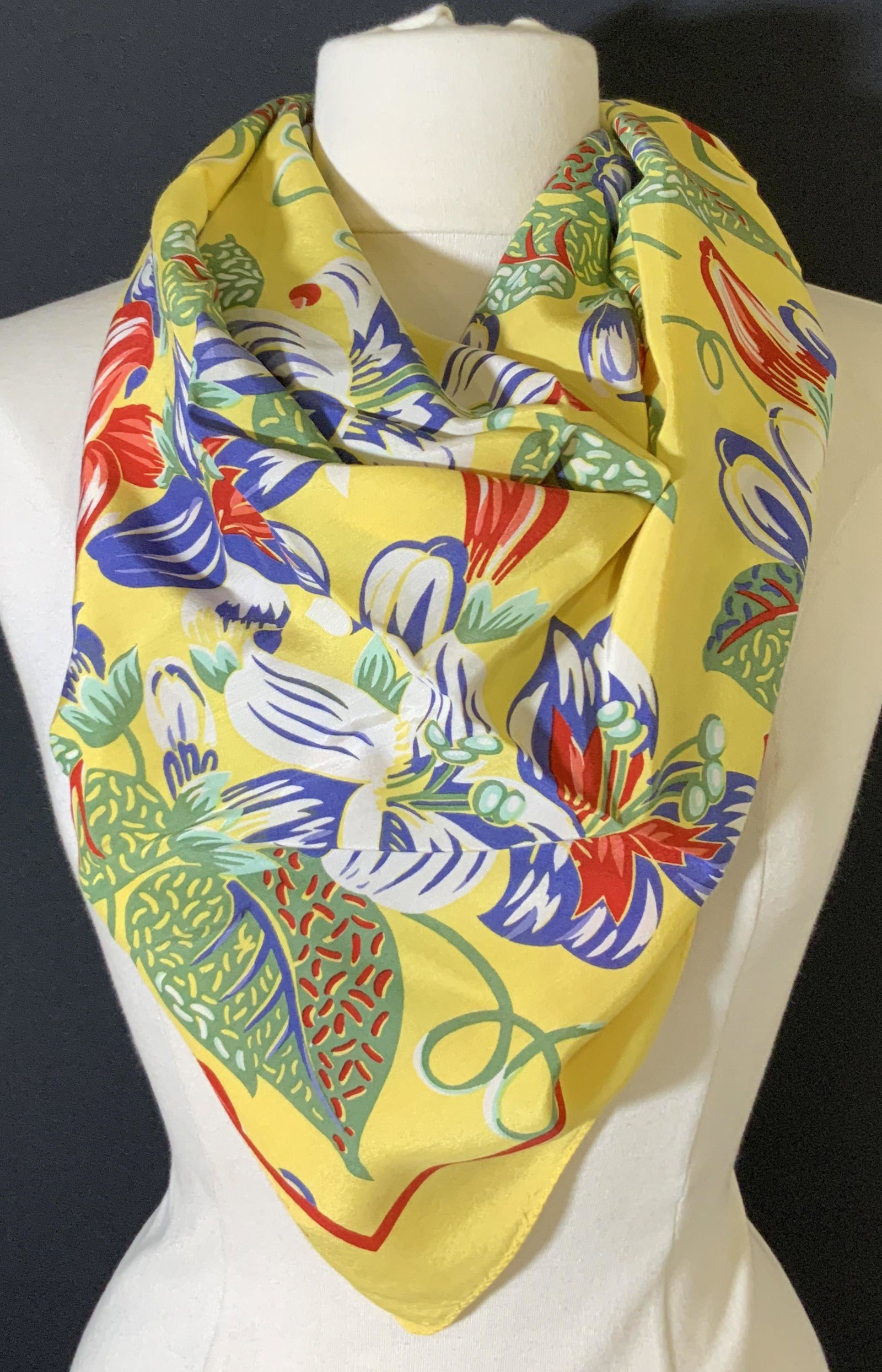 RALPH LAUREN Yellow Floral Square Scarf: Yellow square scarf with red, blue, white, and green floral motifs throughout. Red boarder around floral designs. Ralph Lauren name printed on scarf near boarder. Tags read: POLO RALPH LAUREN. 100% RA