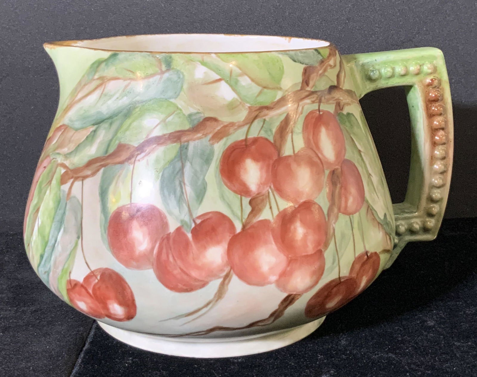 LIMOGES FRANCE Antique Cherry Motif Cider Pitcher: Antique hand painted porcelain jug with embossed decorative porcelain handle. Hand painted designs feature cherries in bunches and duos hanging from branches. Gilt line work around rim of the jug. Und