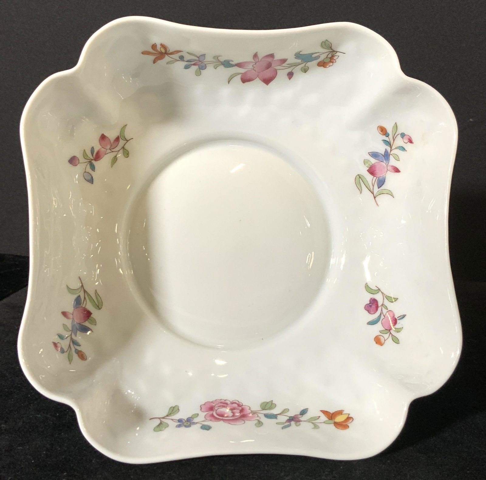 BERNARDAUD LIMOGES Signed Porcelain Footed Dish: Scalloped porcelain dish atop a metal silver toned, possibly plated, base. Porcelain has embossed designs all throughout. Decorative floral details adorn the interior and exterior sides. Flowers are p