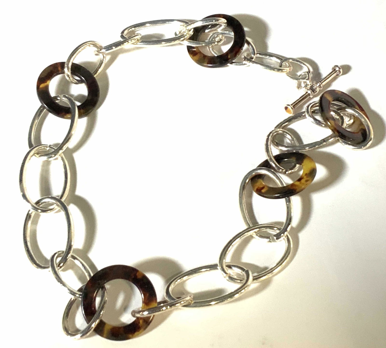 RALPH LAUREN Tortoise Shell Style Link Necklace: Silver tone necklace with oval shaped chain. Circle tortoise style accents throughout chain design. Adjustable bar closure. Approx length: 22 in. Links approx. 1 in. width. Ralph Lauren, Ralph Lauren