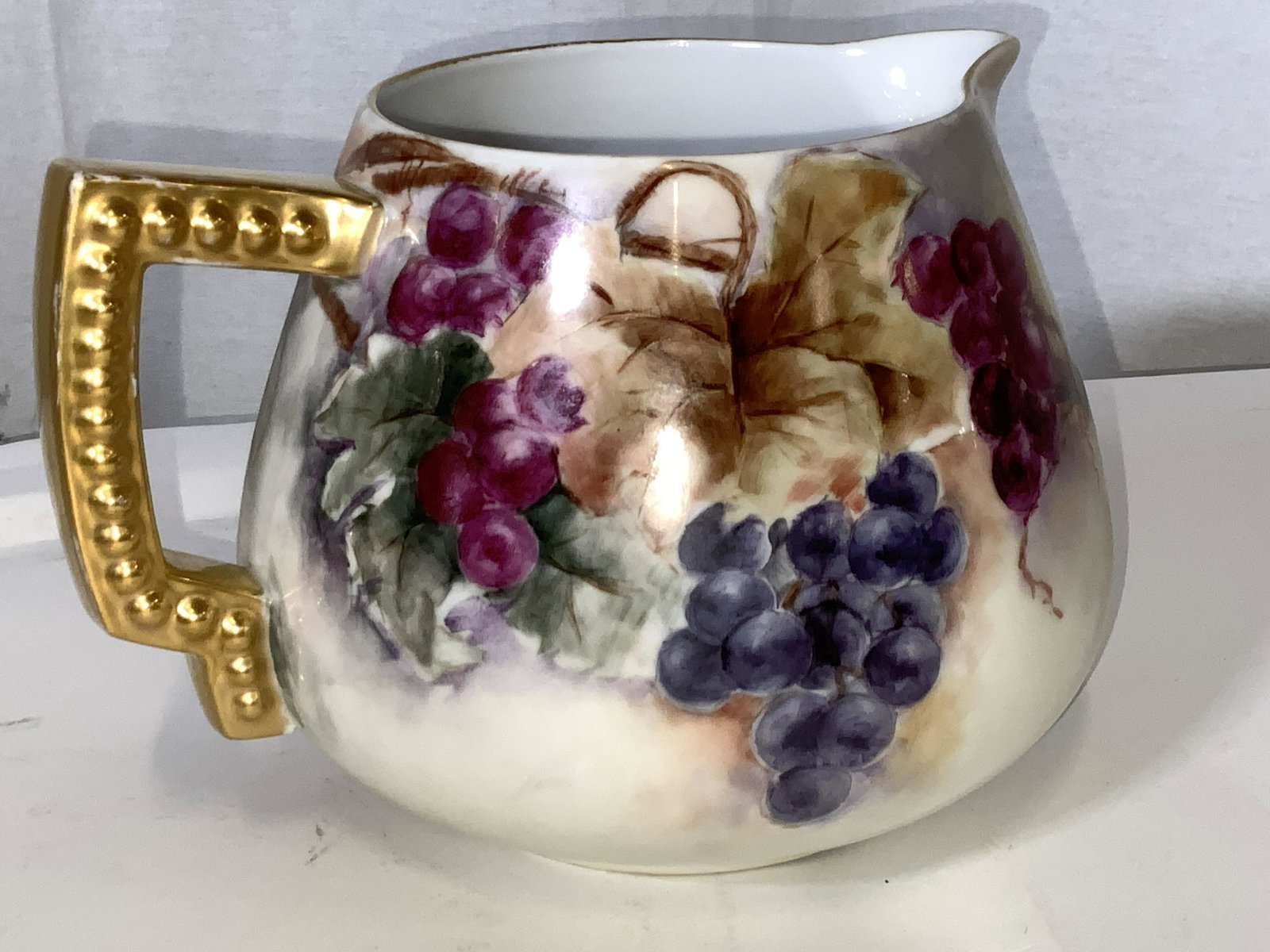 Hand Painted Porcelain Cider Pitcher: A gilded handle with hob knob design. White fine bone China hand painted with vineyard grapes with muted background colored. Typically cider pitchers or jugs were used to serve fresh squeezed juices o