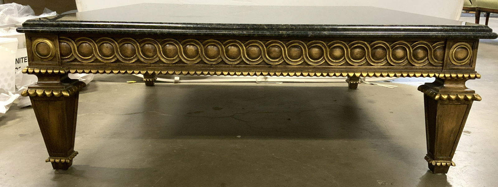 French Louis XVI Marble Top Coffee Table: Table is vintage possibly antique. Base of table is gold leafed and has intricately carved geometric detail. Table has Louis XVI style. Piece has black and gold toned marble top. Table is significantl