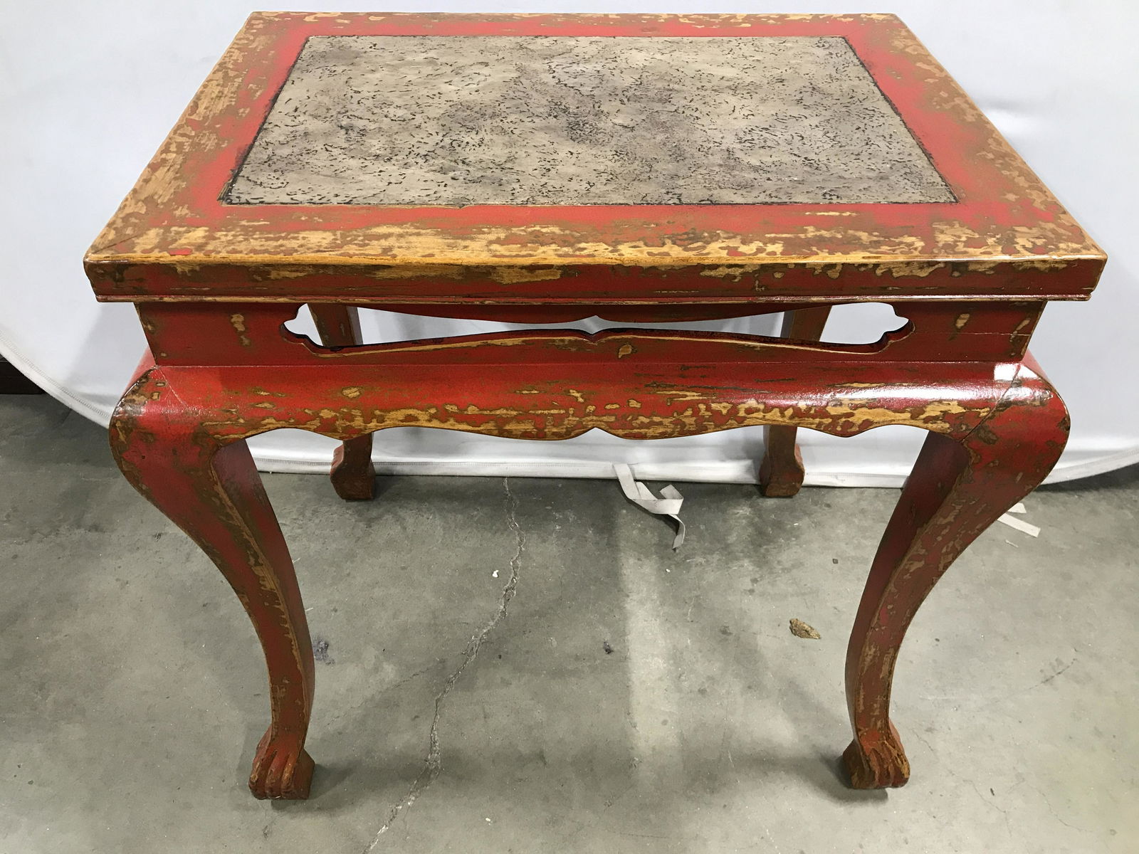 Vintage Asian Carved Wooden Table: Table is vintage possibly antique. Table is red toned with carved wooden legs & feet. Center of tabletop has slate tan toned area which mimics appearance of stone. Table has pierced detail around uppe