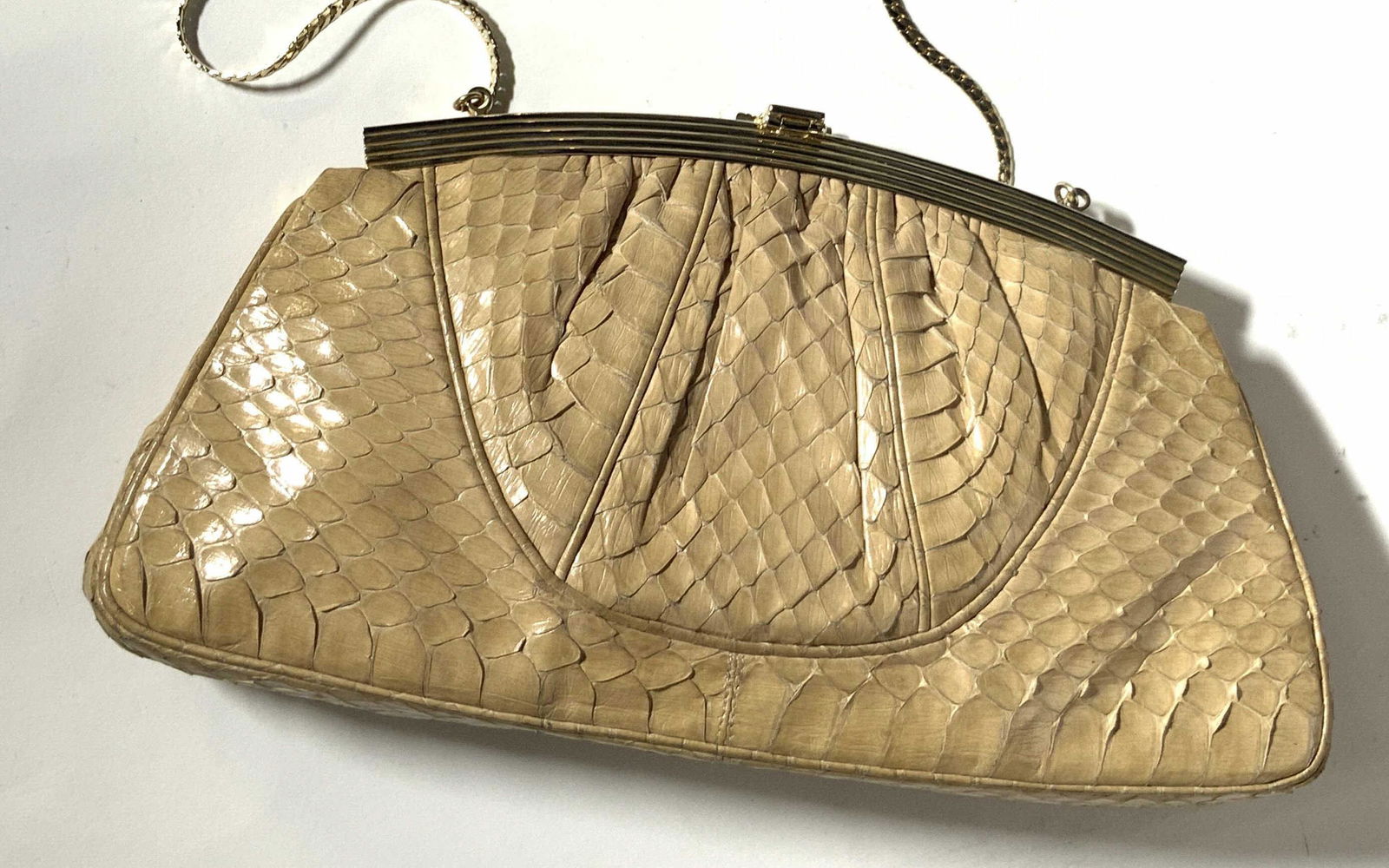 JUDITH LEIBER Vintage Beige Snakeskin Purse: Vintage beige shoulder purse, possibly snakeskin, with gold toned hardware. Snap closure with decorative black adornment depicting a helmet. Strap is long, thin polished gold tone chain. Interior of p