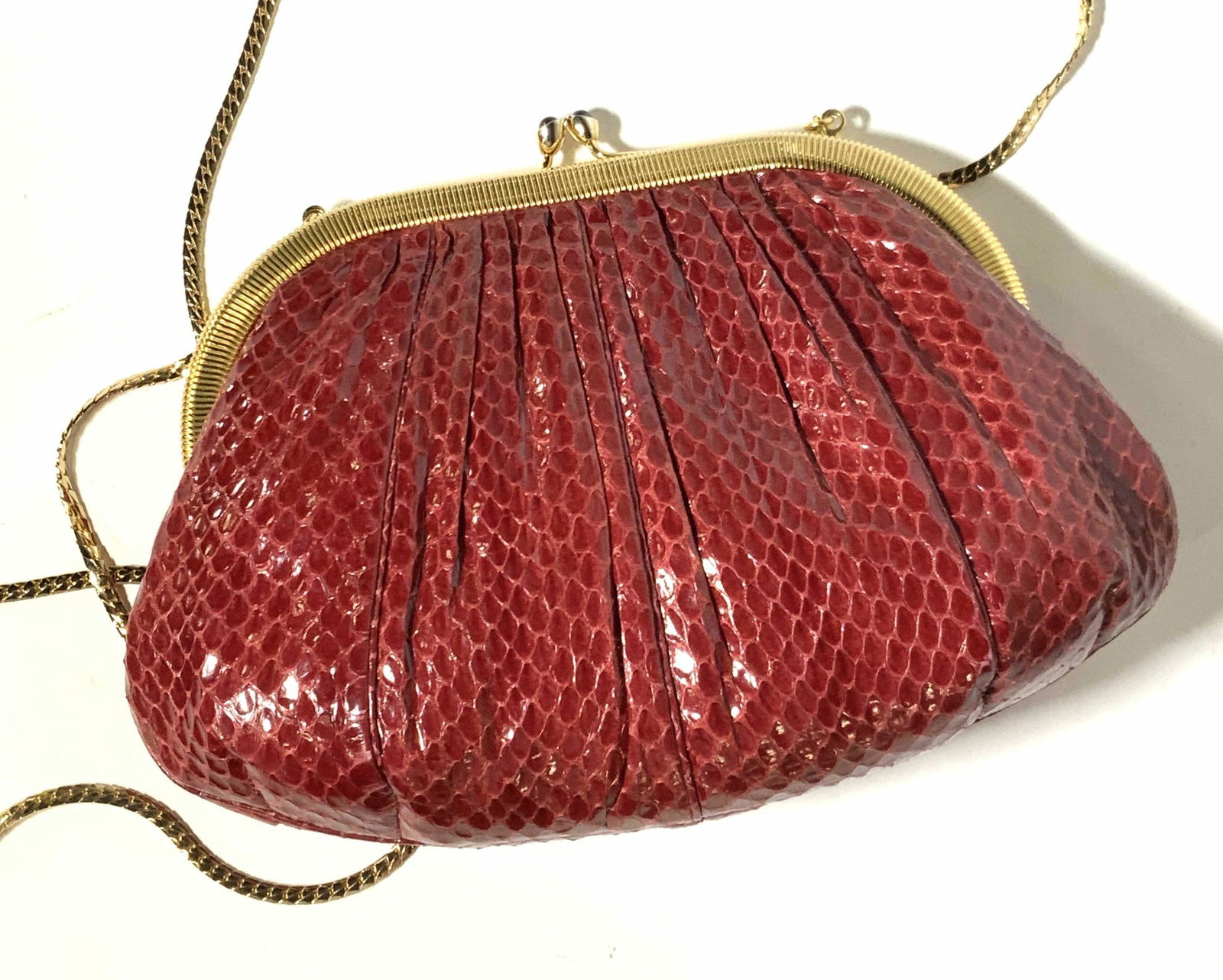 JUDITH LEIBER Red Snakeskin Purse, Original Box: Red snakeskin shoulder purse with gold toned hardware. Snap closure with decorative red cabochon adornments. Strap is long, thin polished gold tone chain. Interior of purse is fully lined with red tex
