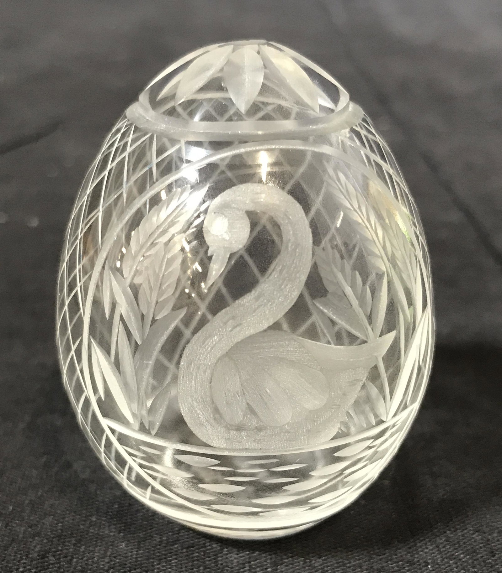 Etched Glass Faberge Egg: Etched Glass Faberge egg, front of egg depicts a swan in water with reeds surrounding it, cross cross pattern throughout egg design, top of egg has a flower design in glass, measures 2.25 inches tall,