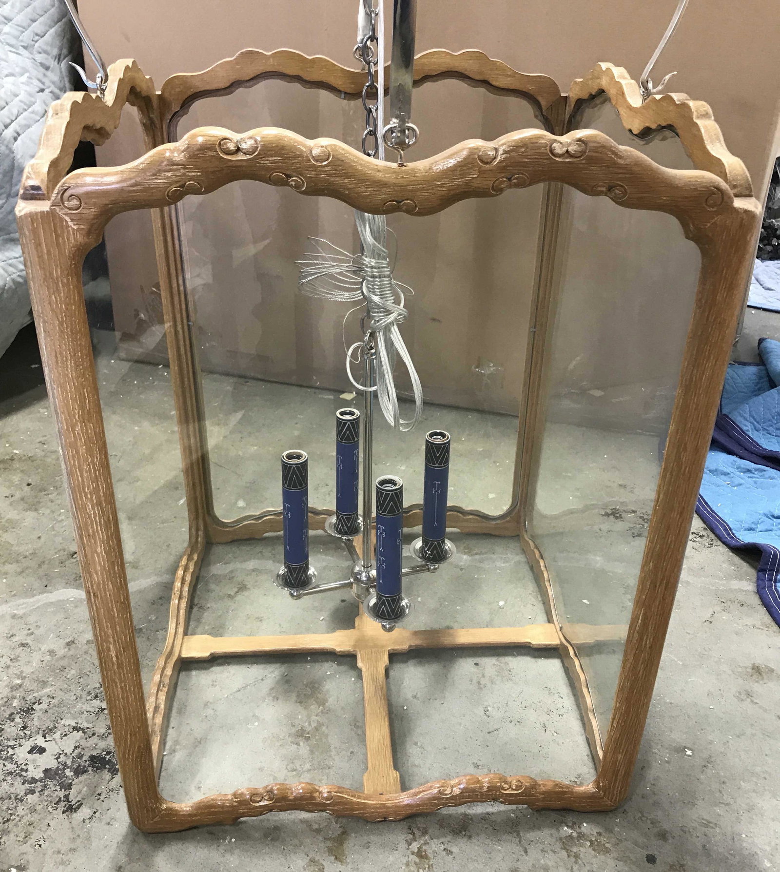 Wood & Metal Windowed Chandelier: Wood and metal chandelier. Wood frame is carved, houses several windows, one glass pane needs replacing. Four polished metal arms hold the wood frame. The socket cluster is suspended within the wood f