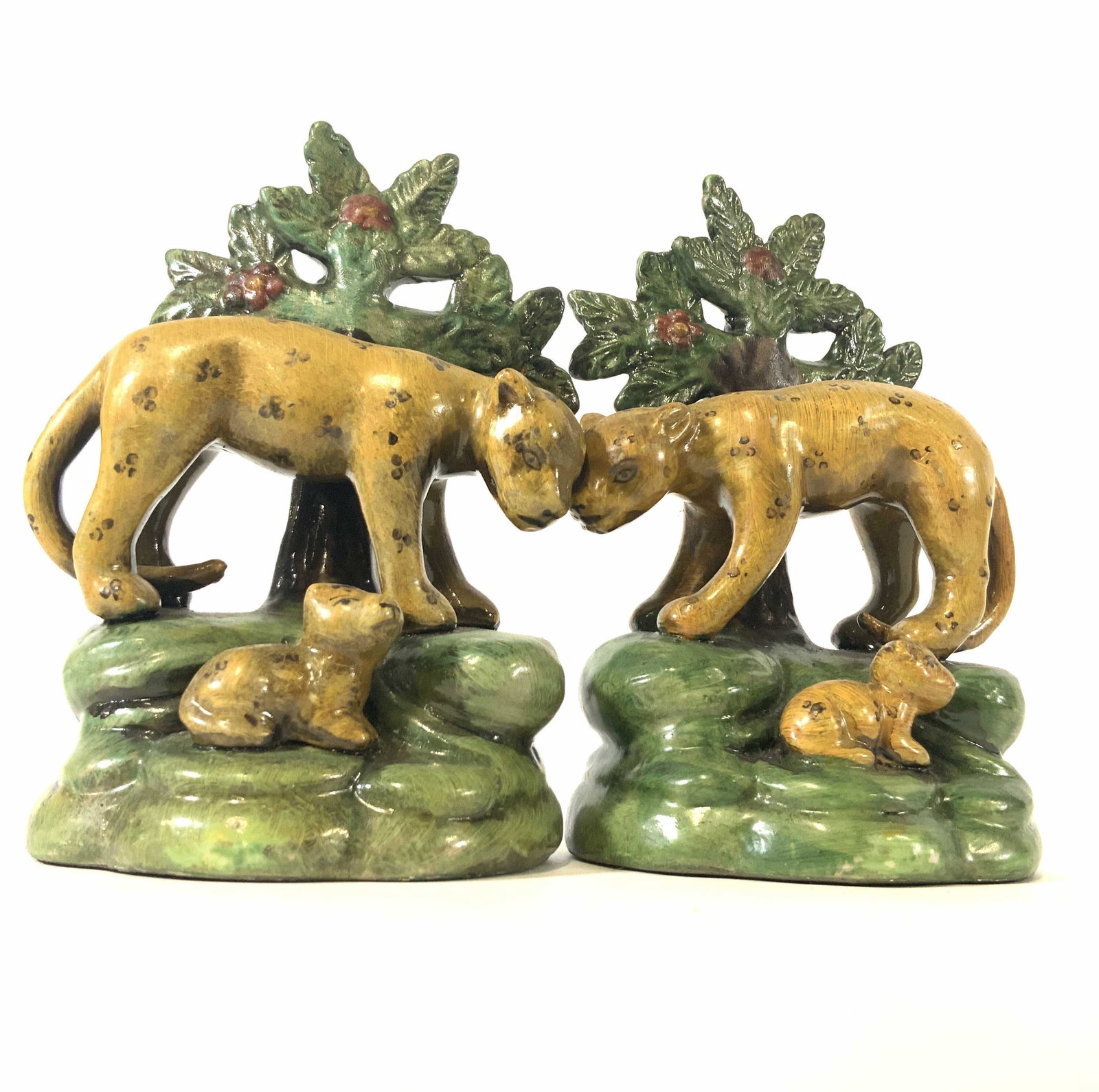 Pair Antique Porcelain Leopard & Cub Figurals: Possibly antique Staffordshire Leopard & Cub Figurals. Pair of hand painted figurals depicting a mother leopard standing over her cub. Both figurals sit and stand atop a green mound. Behind them is a 