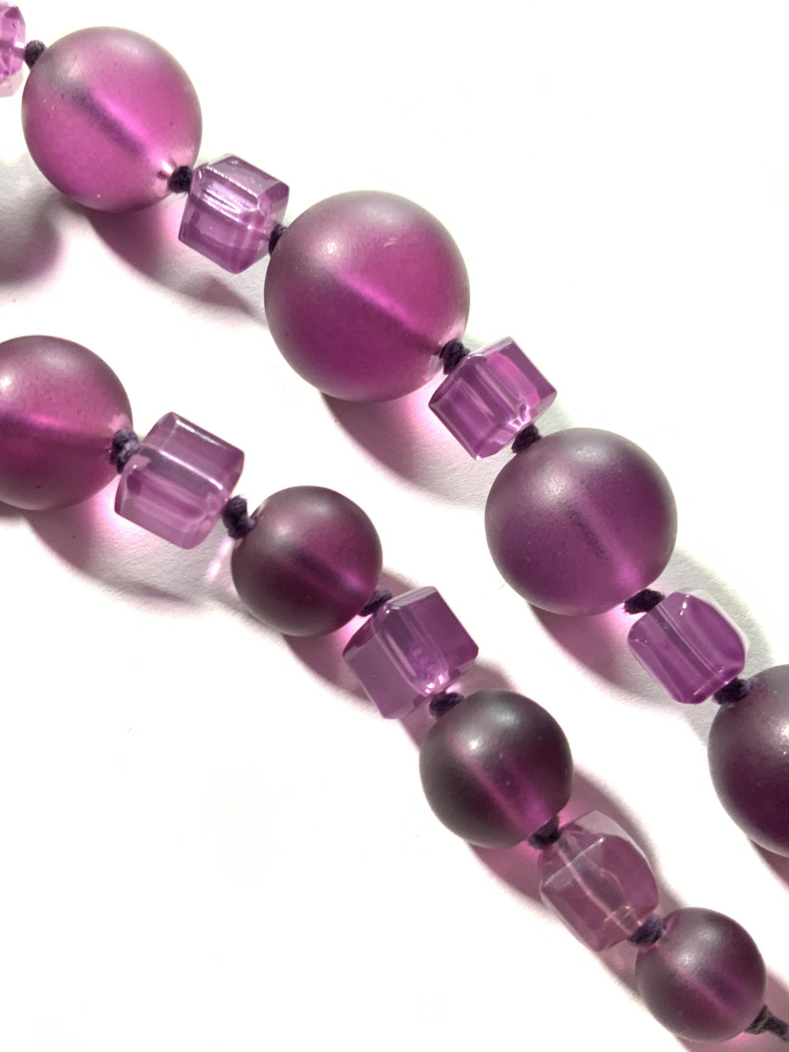 ROBERT ROSE Jewelry Vintage Purple Beaded Necklace: Circular and square beads strung along a purple strand. Circular beads are graduated towards the center. The lobster clasp fastening is polished silver tone and is adjustable. Along chain near clasp i