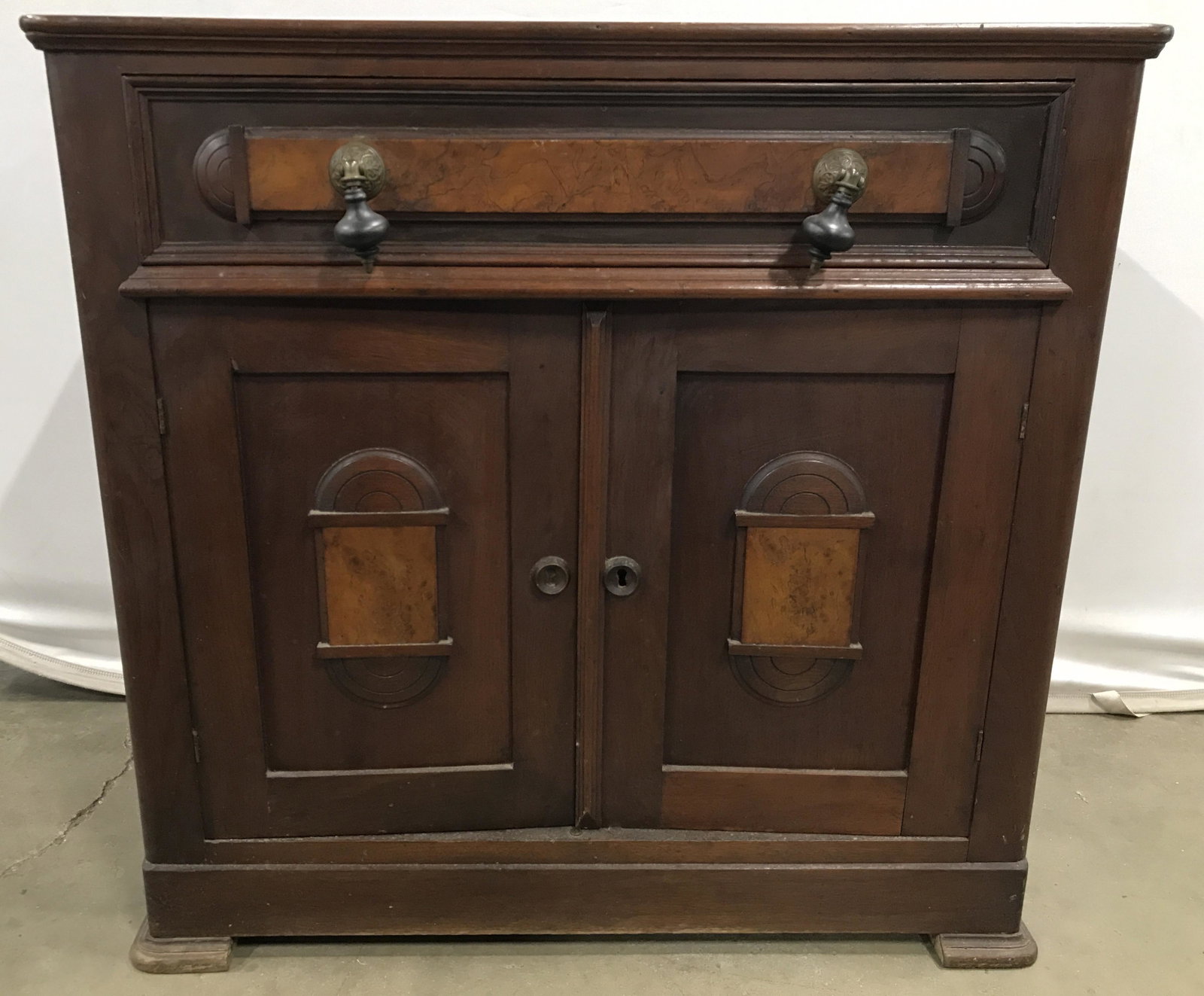 Vintage Wooden Sideboard W Drawer: Sideboard is vintage possibly antique. Piece is brown toned and wooden. Piece has carved detail on cabinet doors & drawer. Drawer has hand Dovetailing. Cabinet doors have key holes. Drawer has danglin