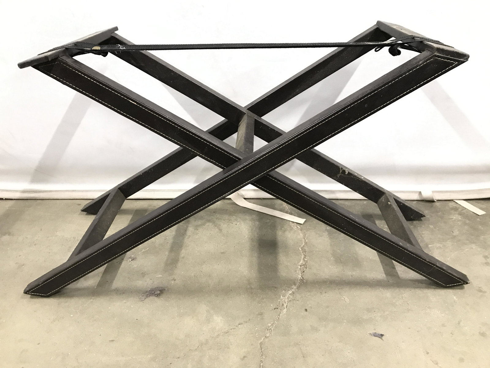 Vintage Leather Bound Folding Luggage Rack: Luggage rack is brown toned and bound in what appears to be leather. Luggage rack has x shaped structure. Piece measures approximately 35 inches long, 18 inches tall 15 inches deep. Luggage rack, leat