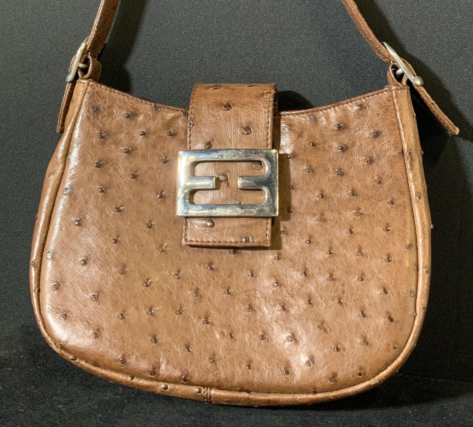 ARTBAG Deep Brown Spotted Women’s Handbag: A brown, spotted purse that is possibly made from Ostrich. Spots are in relief of clutch. One snap button closure. Interior is a lighter brown material. Interior tag reads: Artbag Creations, 735 Madis
