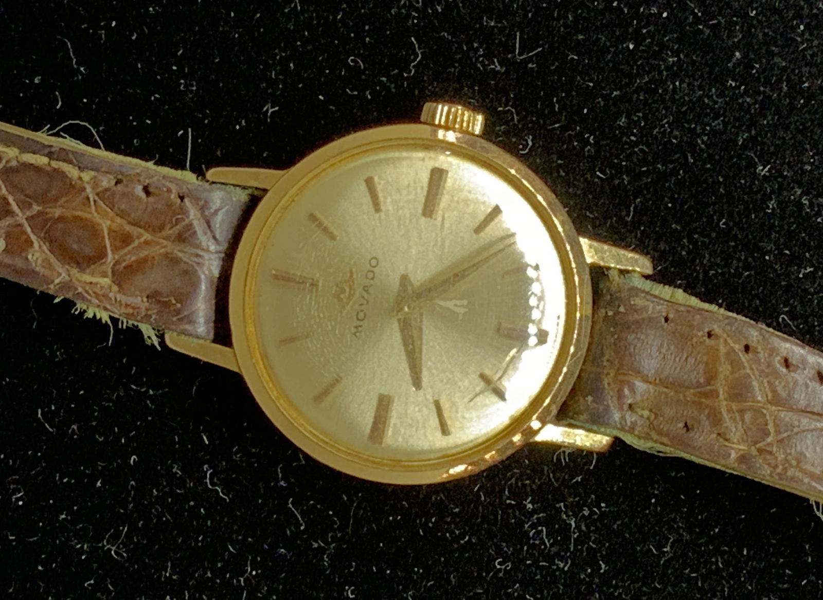 Vintage MOVADO Ladies Watch, Jewelry Accessory: Gold toned MOVADO watch, Signed ‘M- Movado’ and also reads ‘ Switzerland’ Wind up. Watch face measures 7/8 in. Reptile leather strap, fits 9 mm. Length 7.5. - 6.5 for wrist. Glass has wear con