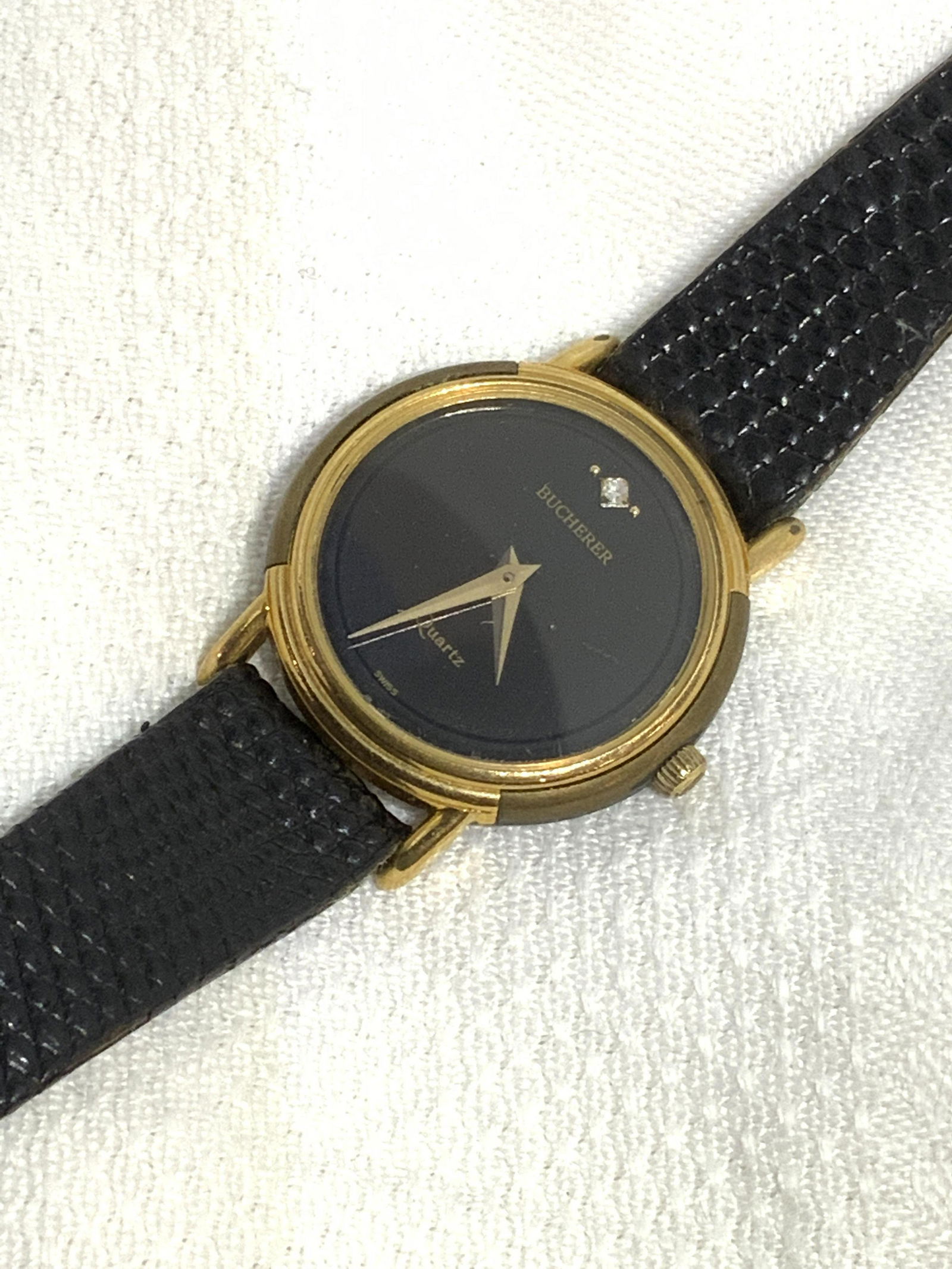 BUCHERER Vintage Swiss Quartz Ladies Wristwatch: Carl Bucherer Luxury Black and Gold Tone Metal Wristwatch with accent crystal ( possibly) under glass. Signed Bucherer- Quartz- Swiss on watch face, verso reads stainless steel back, Swiss Made, Swiss