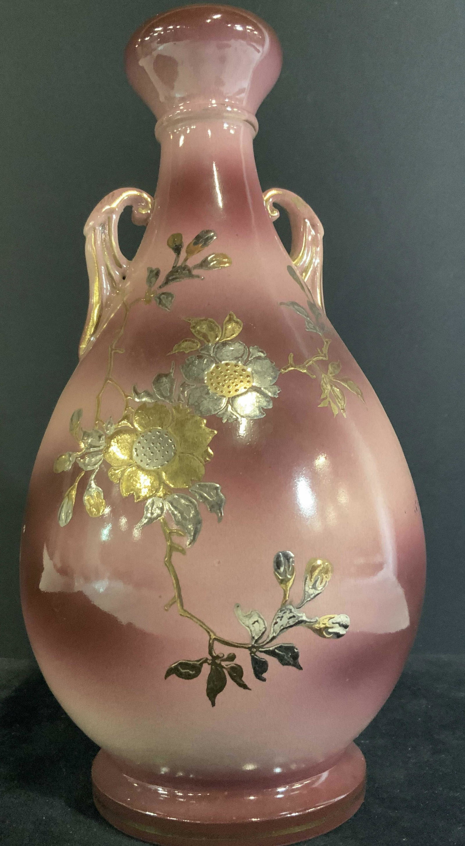 Floral Amethyst Ombré Porcelain Tabletop Vase: Ombré amethyst design porcelain vase. Larger base that tapers to a more narrow neck. Gold and silver tone florals and leaves along vines and branches. In relief gilt line work throughout. Handles are