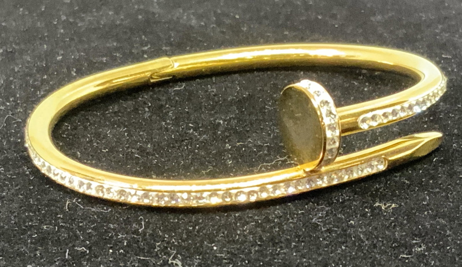 Curled Nail Form Bracelet, In Style of CARTIER: c1970. yellow gold toned metal lined with brilliant crystals. Hinges open, one side snaps into the nail 2.5 in diameter. Hairline head area just over .5 in wide ‘Juste un Clou Cartier Style Fashion 