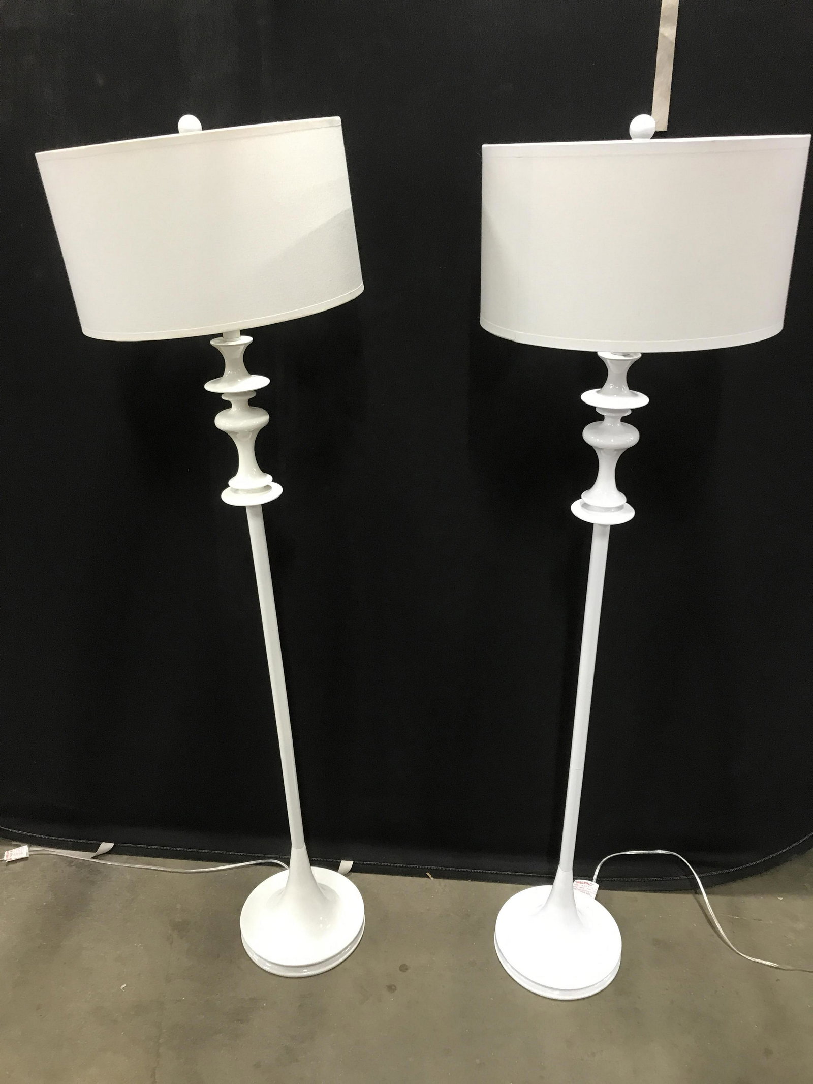 Pair White Toned Floor Lamps W Shades: Pair of white toned floor lamps. Each measures approx 58 inches H, and 16 inches in diameter. Wear is consistent with age and use. Home lighting, vintage decor, decorative accessories, decorative arts