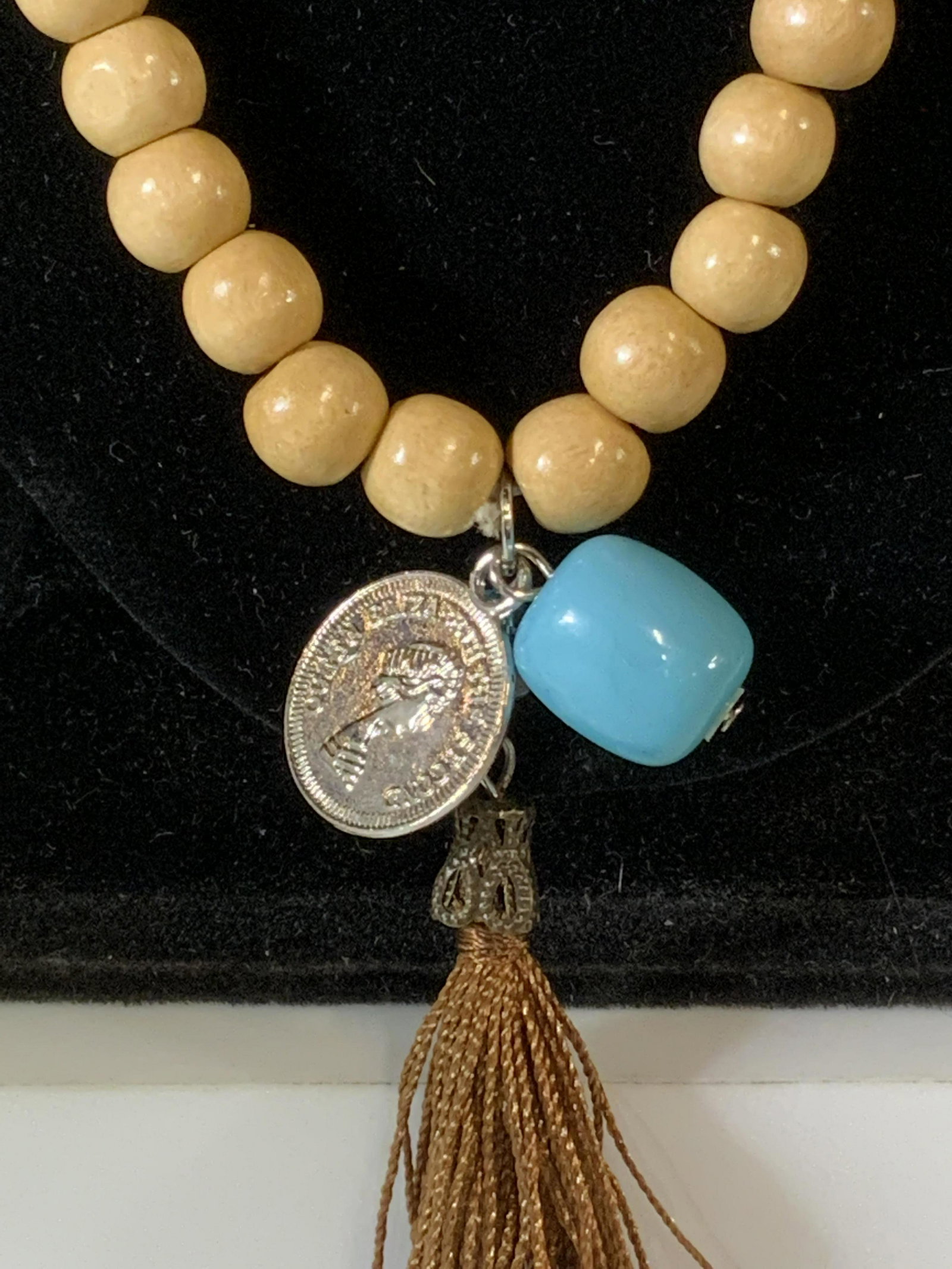 Beaded QE2 COIN & Tassel Beaded Necklace, Jewelry: Artisanal Light colored beaded necklace, shellacked beaded with several pendant that include a bronze thread tassel, a turquoise color bead, and a lightweight metal coin on Queen Elizabeth II profile.