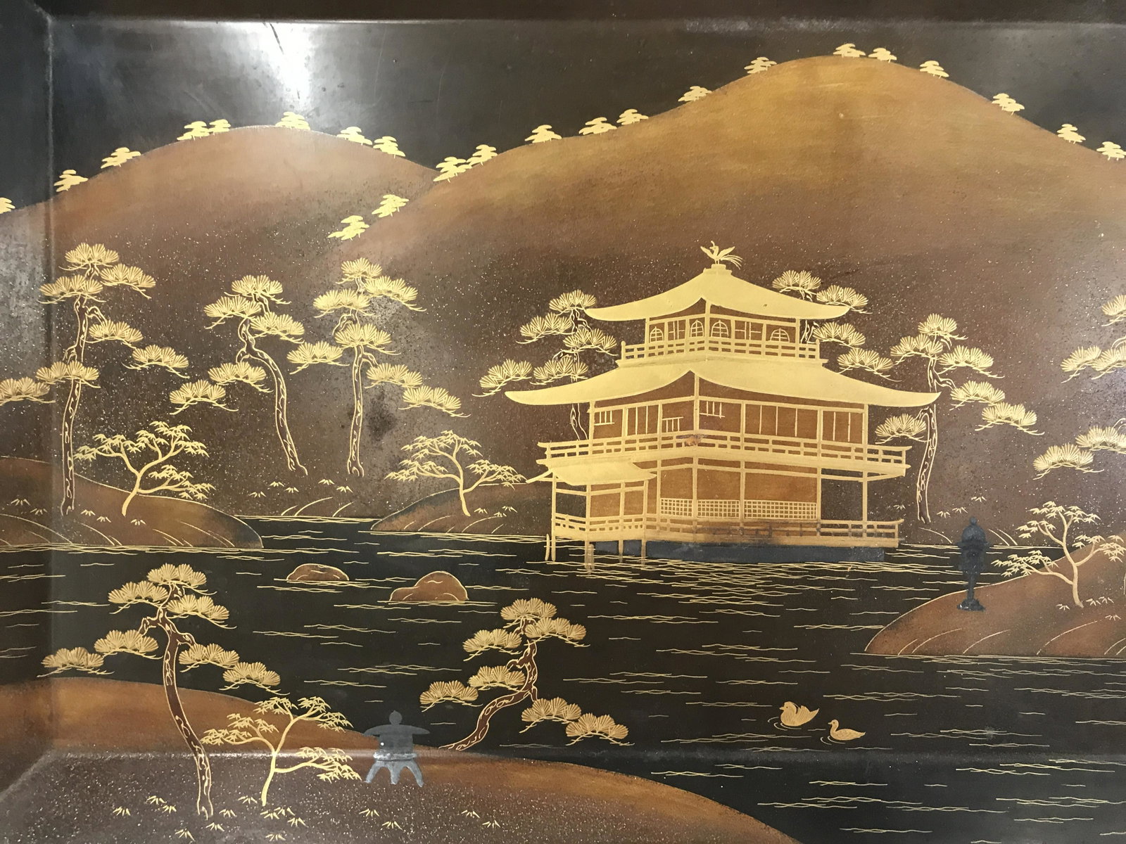 Signed Asian Lacquered Tray & Stand: Signed asian tray. Hand painted lacquer finish, signed on its underside, in asian characters. Stand is crafted from metal. Gilt paint is used to depict a lakefront home. Measures approx 11.5 inches H,
