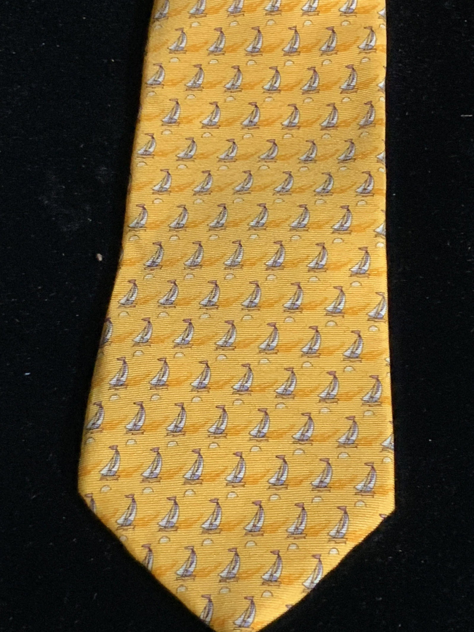 TOMMY HILFIGER Silk Boat Pattern Tie: A yellow tie with a repeating boat pattern throughout. One tag reads: TOMMY HILFIGER. Another tag is marked with their trademark, and the underside reads: 100% silk. The interior of the tie has green 