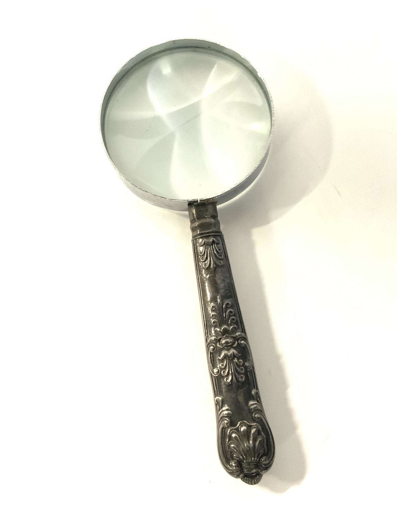 Handheld Signed Sterling Silver Magnifying Glass: Handheld magnifying glass. Hallmarked sterling silver. Hallmarks are a crown and a lion. The handle is decorated with embossed metal designs. Weight: 2.44 ozt. Approx. Height 6 in. Approx. Width 2.5 i