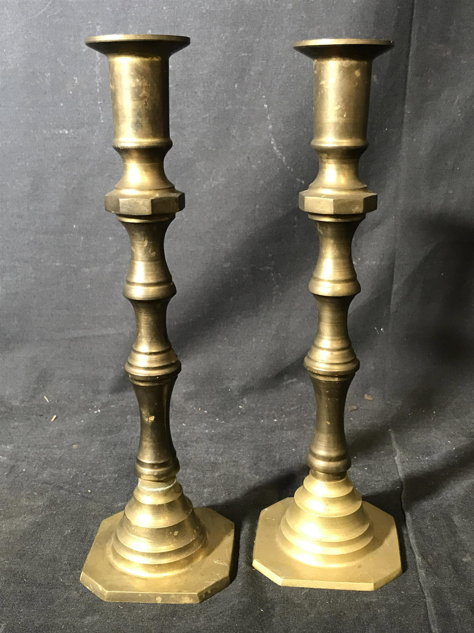 Pair Brass Toned Metal Candlestick Holders: Pair Brass toned Metal Candlestick holders, two nearly identical candle holders with come tarnish to the surface, both measure approximately 11 inches at tallest point, both have octagonal bases, both