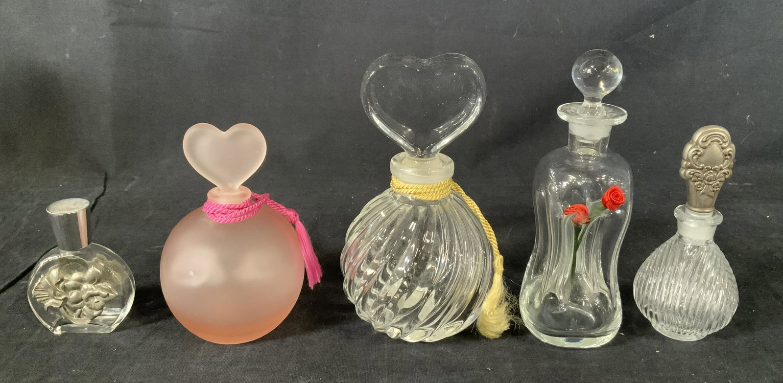 Lot 5 Vintage Art Glass Perfume Bottles: Lot 5 Vintage Glass Perfume Bottles, label to base of clear bottle with heart shaped stopper reads ‘Teleflora’, label to base of pink bottle reads ‘Made in Taiwan for Dept 56’, smallest bottle