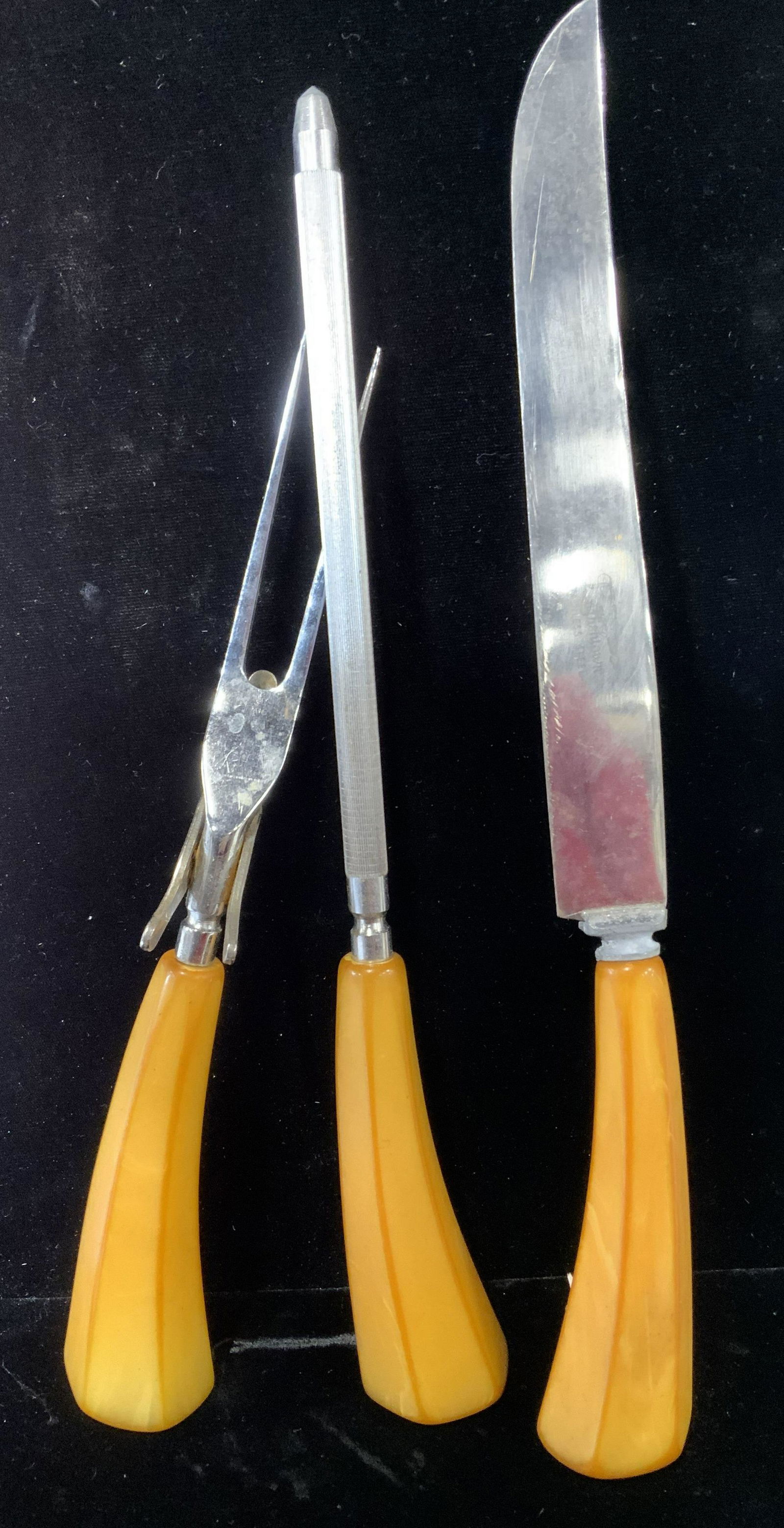 Set 3 ENGLISHTOWN Bakelite Serving Utensils: Yellow Bakelite handles with stainless steel. Carving Knife is hallmarked ENGLISHTOWN Stainless steel. Includes two prong carving fork and knife sharpening utensil. Knife 12.5 in. app. Collectible Bak