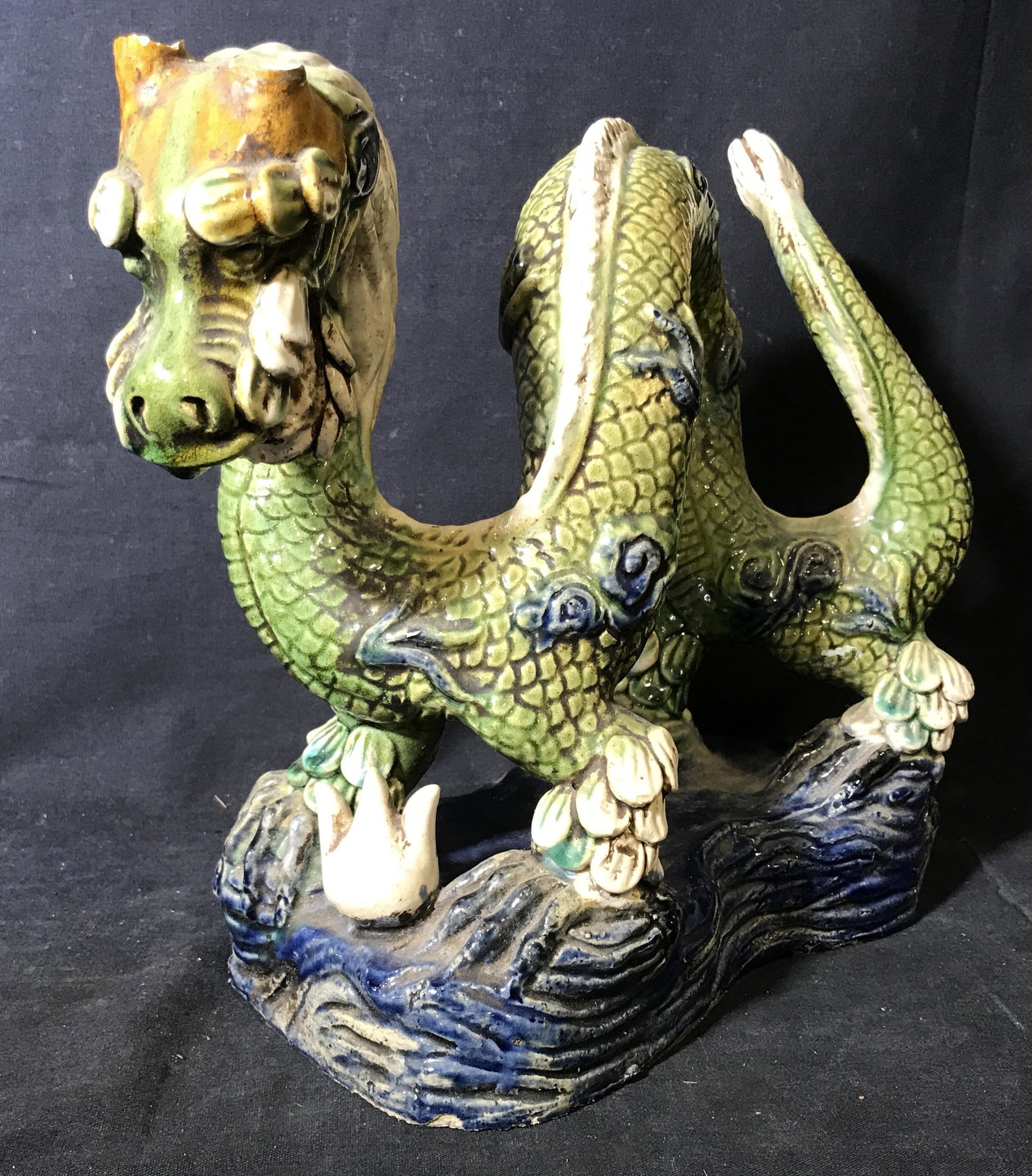 Asian Ceramic Hand Painted Dragon Statue: Ceramic hand painted dragon statue, no apparent signatures or stamps, subject an Asian style dragon on a blue platform looking out with open mouth and wide eyes, horns missing from dragon, dragon pain
