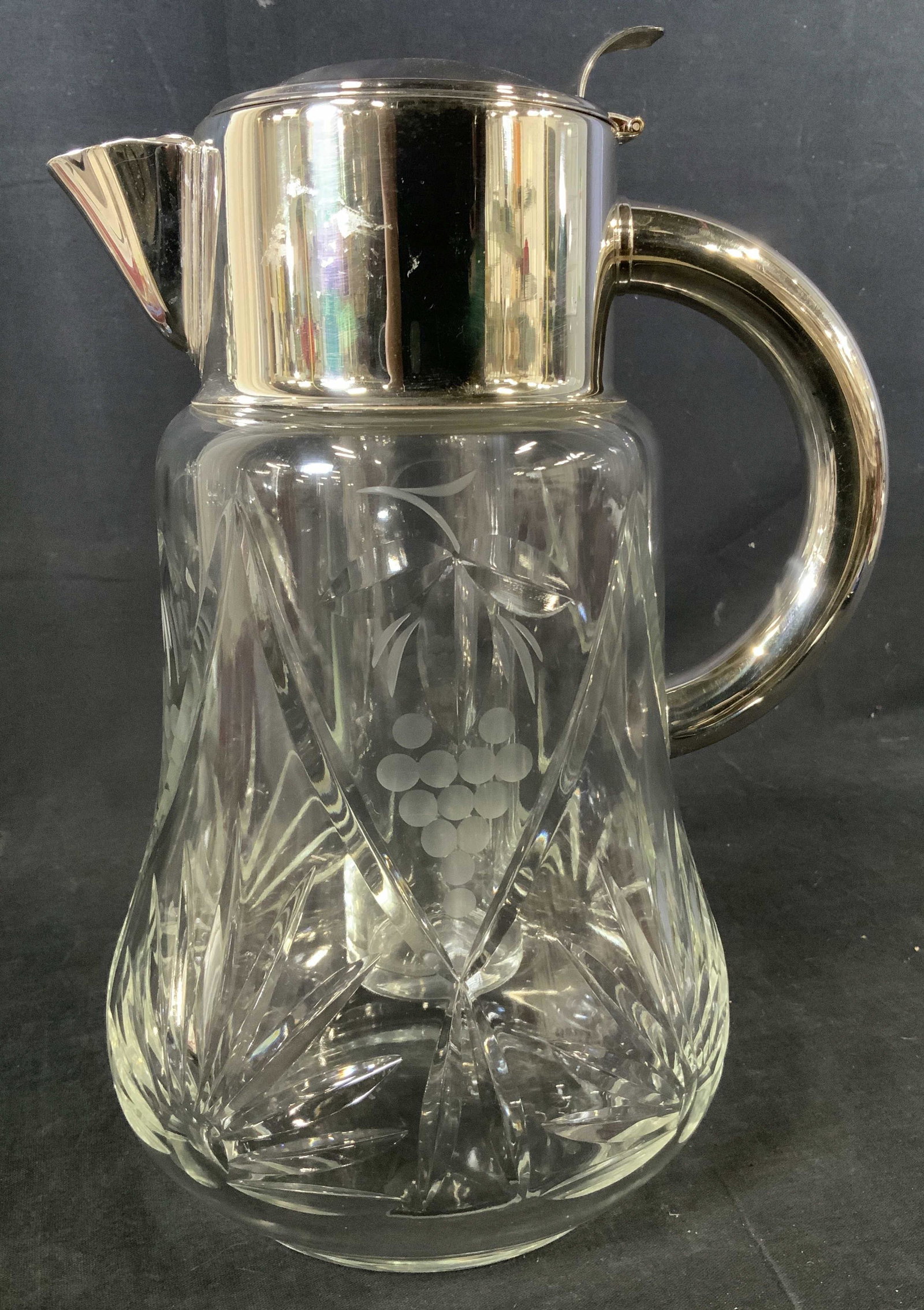 Silver Plated Glass Pitcher, Germany: Silver Plated Glass Pitcher, Germany, inscription to metal reads ‘SilverPlated Made in Western Germany’, design features stylized grapes, measures 11 1/2 x 8 1/2 inches at widest point, some surfa