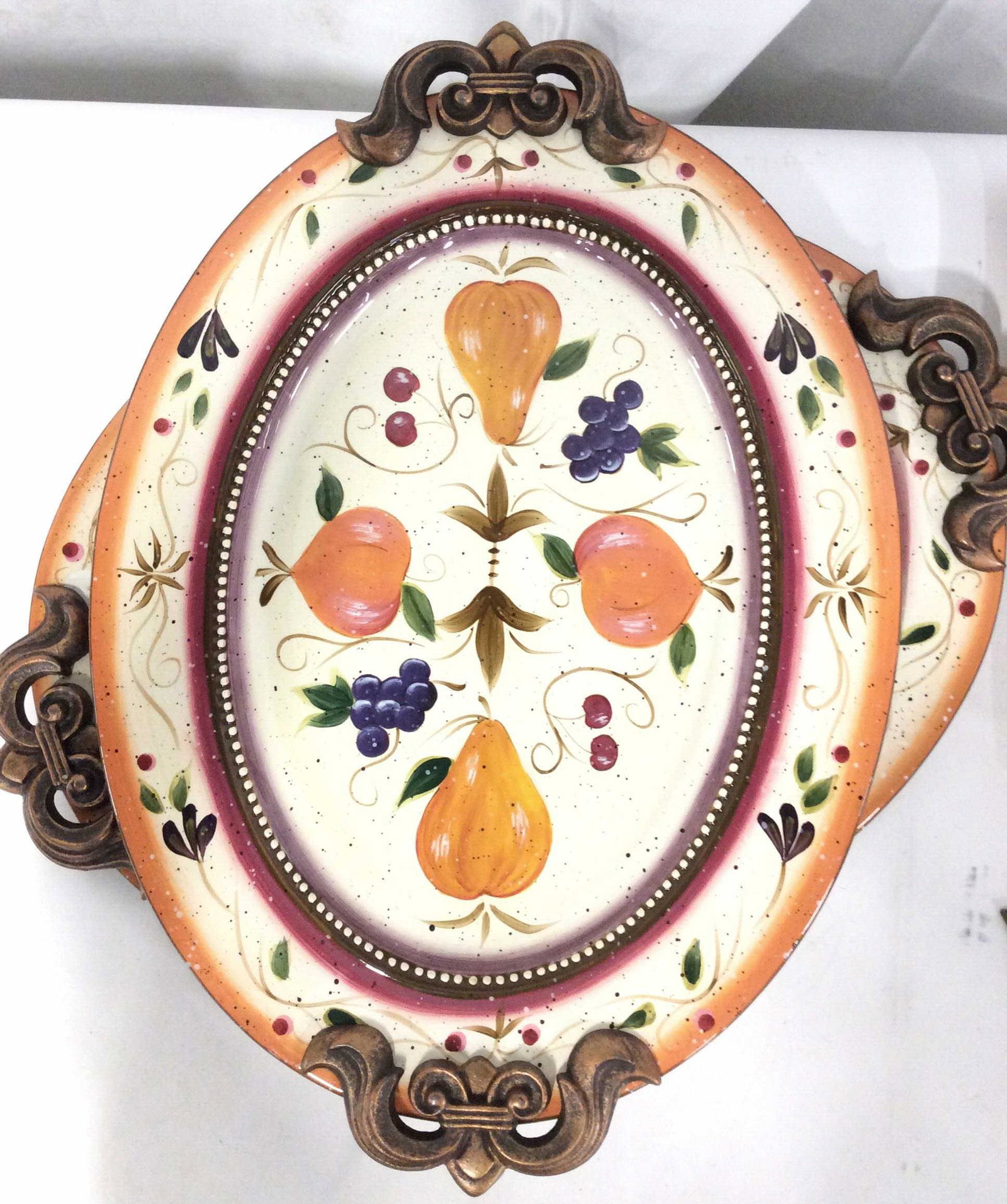 Pair Julie Ueland Enesco Ceramic Platters: BeUtifil Hand Painted Serving Platters, fruit decor, Bronzed washed metal handles, Fleur De Lis Shape, Underside Hallmarked And Reads ‘ 2004 ( copyright symbol) Julie Ueland Licencee Enesco Group In