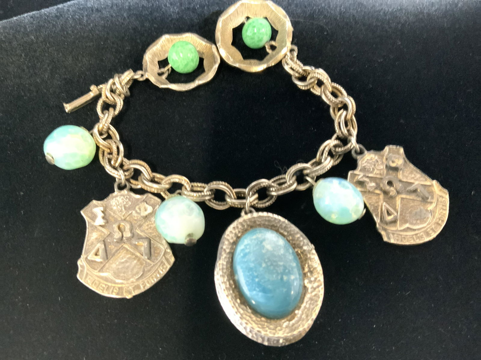 Mid Century Fidelis & Fortis Charm Bracelet: Chunky charms dangle from the bracelet chain, various charms include faux turquoise stone set in hammered silver tone metal and embossed Latin Armor shield that read Fidelis ET Fortis. Dangle app 1-1.