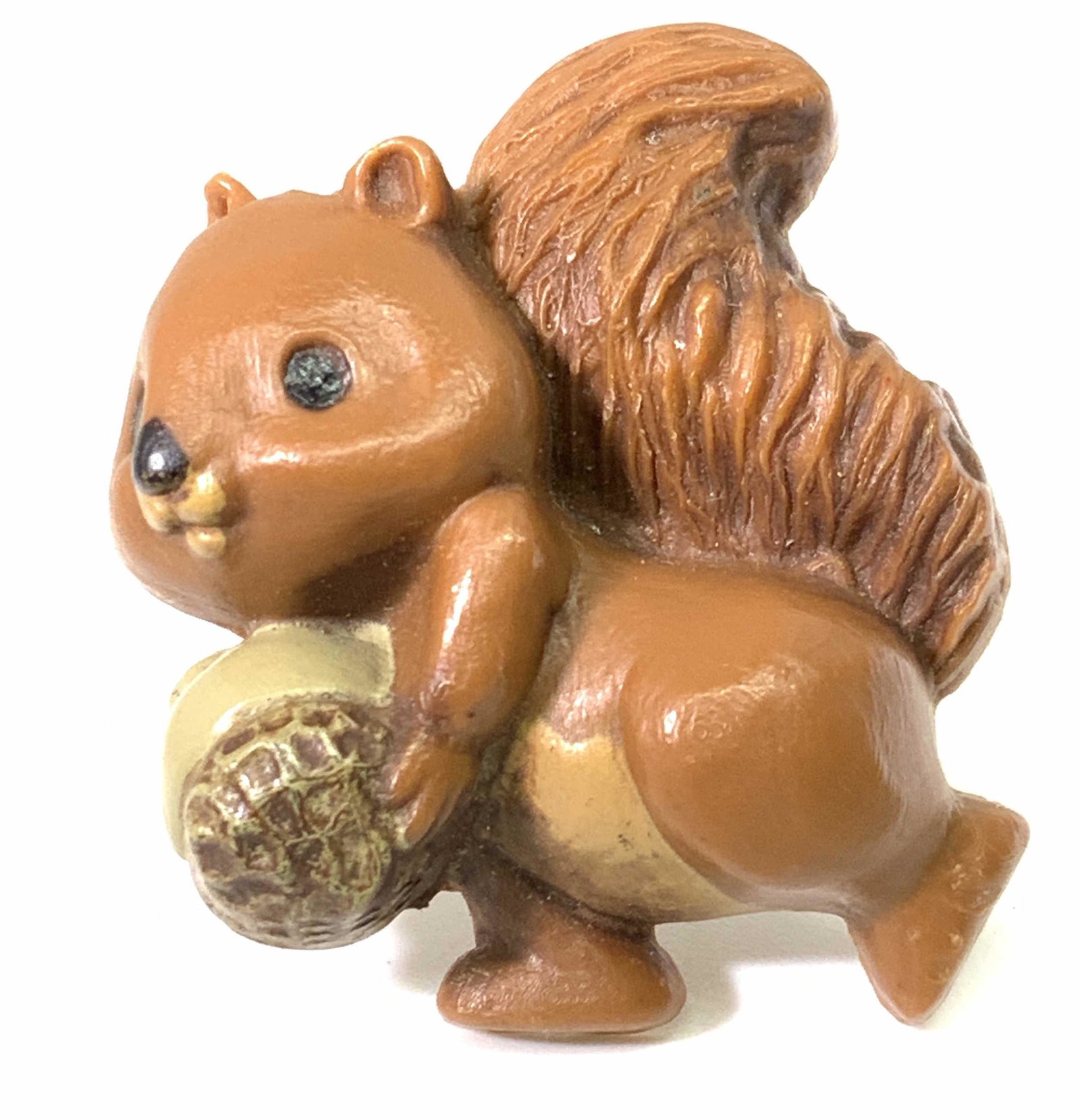 HALLMARK CARDS INC Signed Squirrel W. Acorn Brooch: A composite squirrel form brooch with a pin closure on the underside. The squirrel has an etched tail and in relief facial features. The squirrel is depicted holding an acorn. The underside is signed: