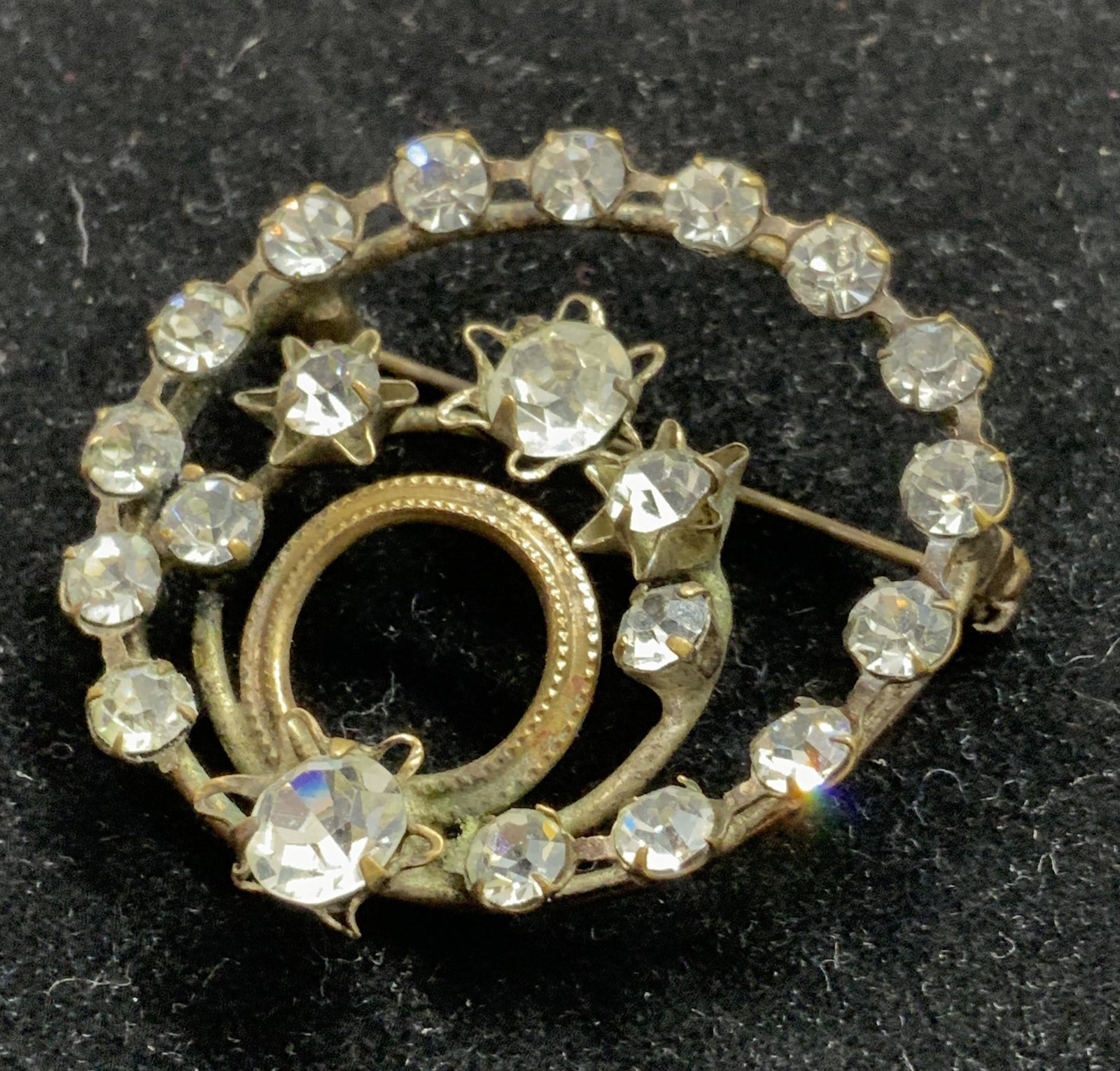 ANTIQUE CRYSTAL CIRCULAR BROOCH, AUSTRIA: C. 1920 Austrian Crystal Brooch, circle within a circle, decorated with solitaire clear crystals in 4 prong setting. Bronze tone base metal. Hallmarked AUSTRIA on verso, 1.25 in diameter. Austrian Cry